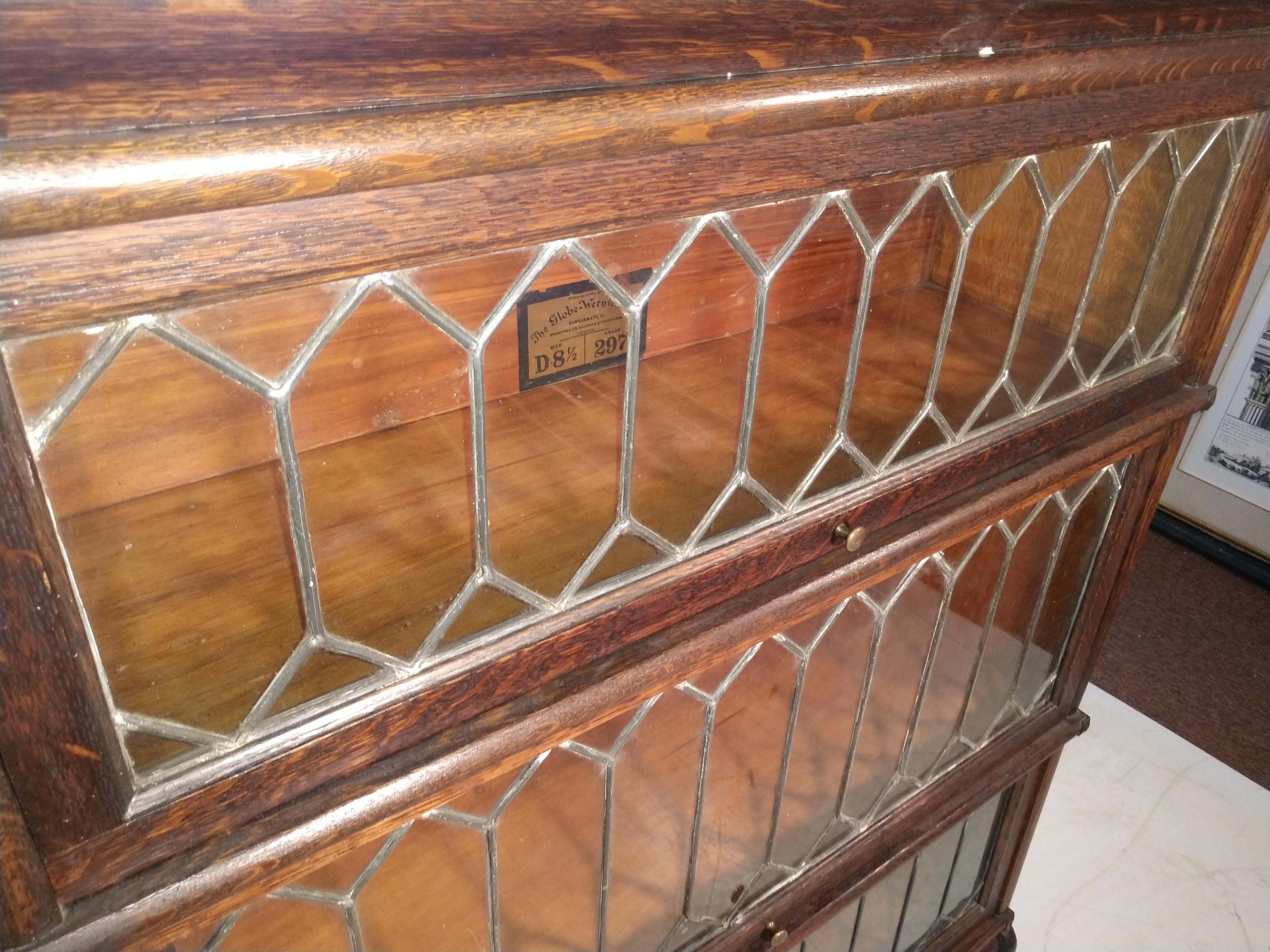 Fabulous leaded glass bookcase by Globe Weinecke C1920. Quarter sawn oak in original finish. Excellent vintage condition with minimal wear. Bookcase consists of 3 storage areas and base which has a drawer and a top bullnose section. Largest is 9.5 D