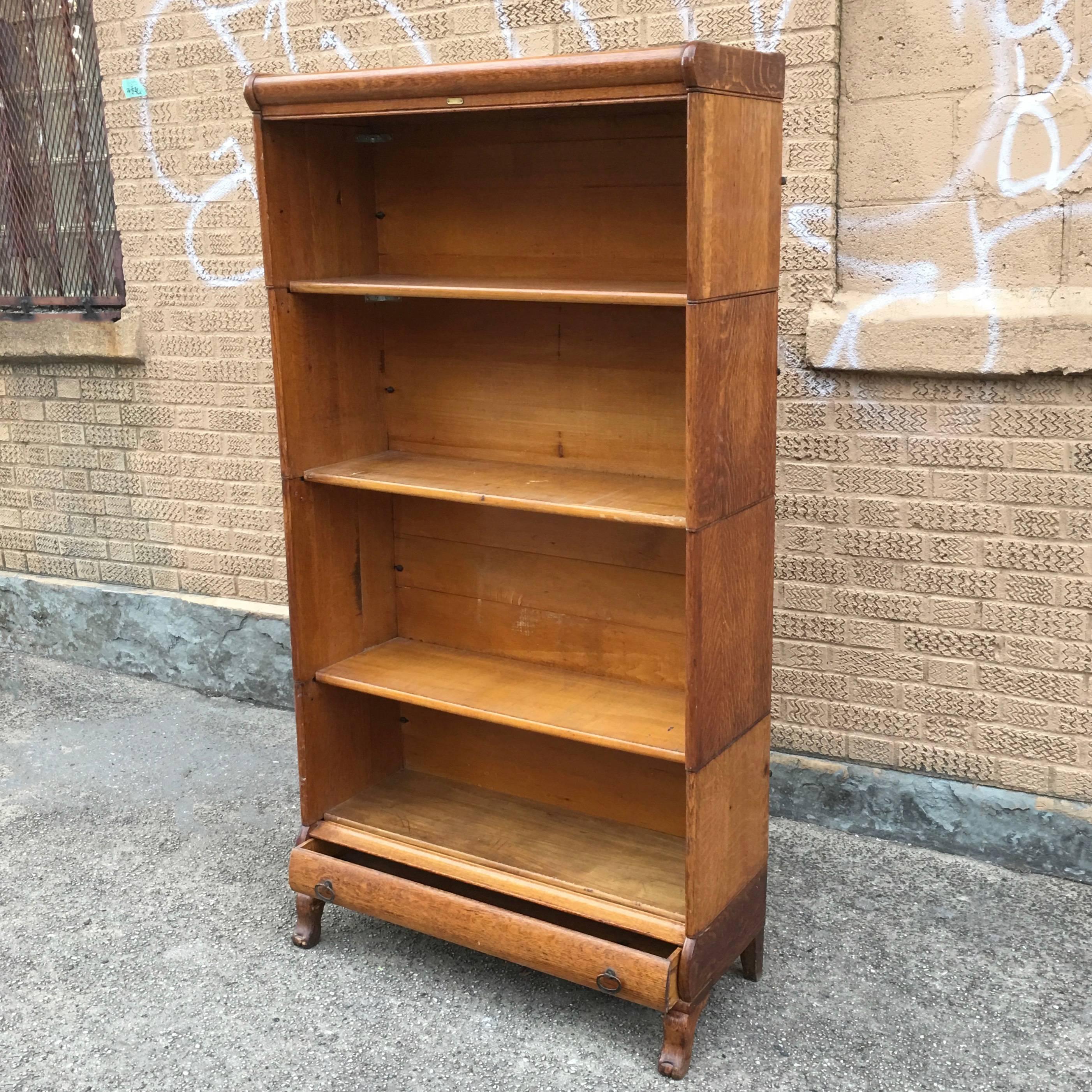 Rare, antique, early 20th century, solid oak, barrister book case by Globe Wernicke features open, modular, stacking shelves with wonderful details and a bottom drawer with brass pulls.  The shelf heights vary from bottom 12.5
