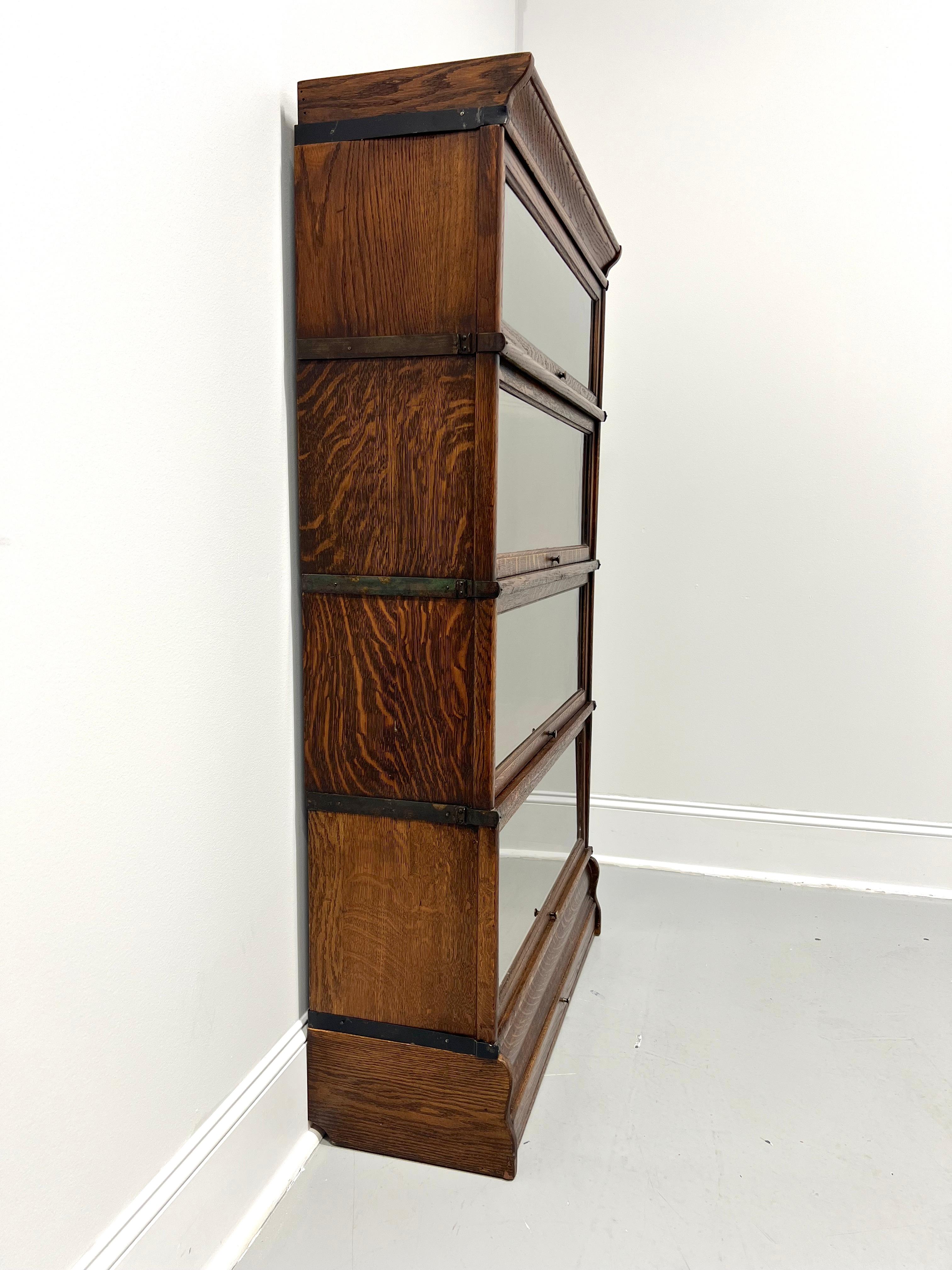 An antique Arts & Crafts style stacking barrister bookcase by Globe Wernicke, of Cincinnati, Ohio, USA. Quartersawn tiger oak with brass knobs and brass side accents/supports. Features crown, four various size stacking flip-up slide-back glass door
