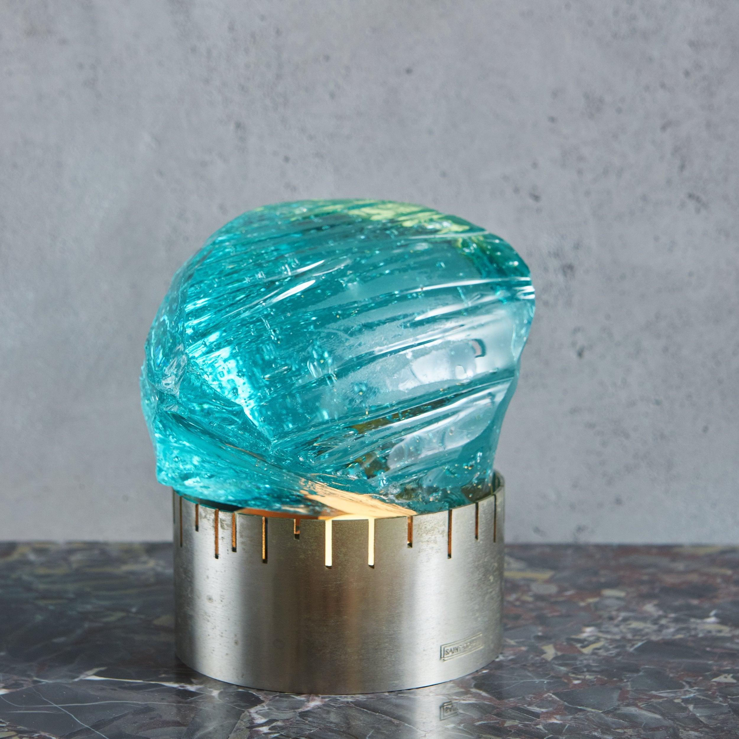 A globular bubble glass table lamp designed by Max Ingrand for the renowned French glass company, Saint-Gobain. This stunning lamp features an organic form, chiseled glass piece that rests upon a round, nickel-plated brass base with notch details.