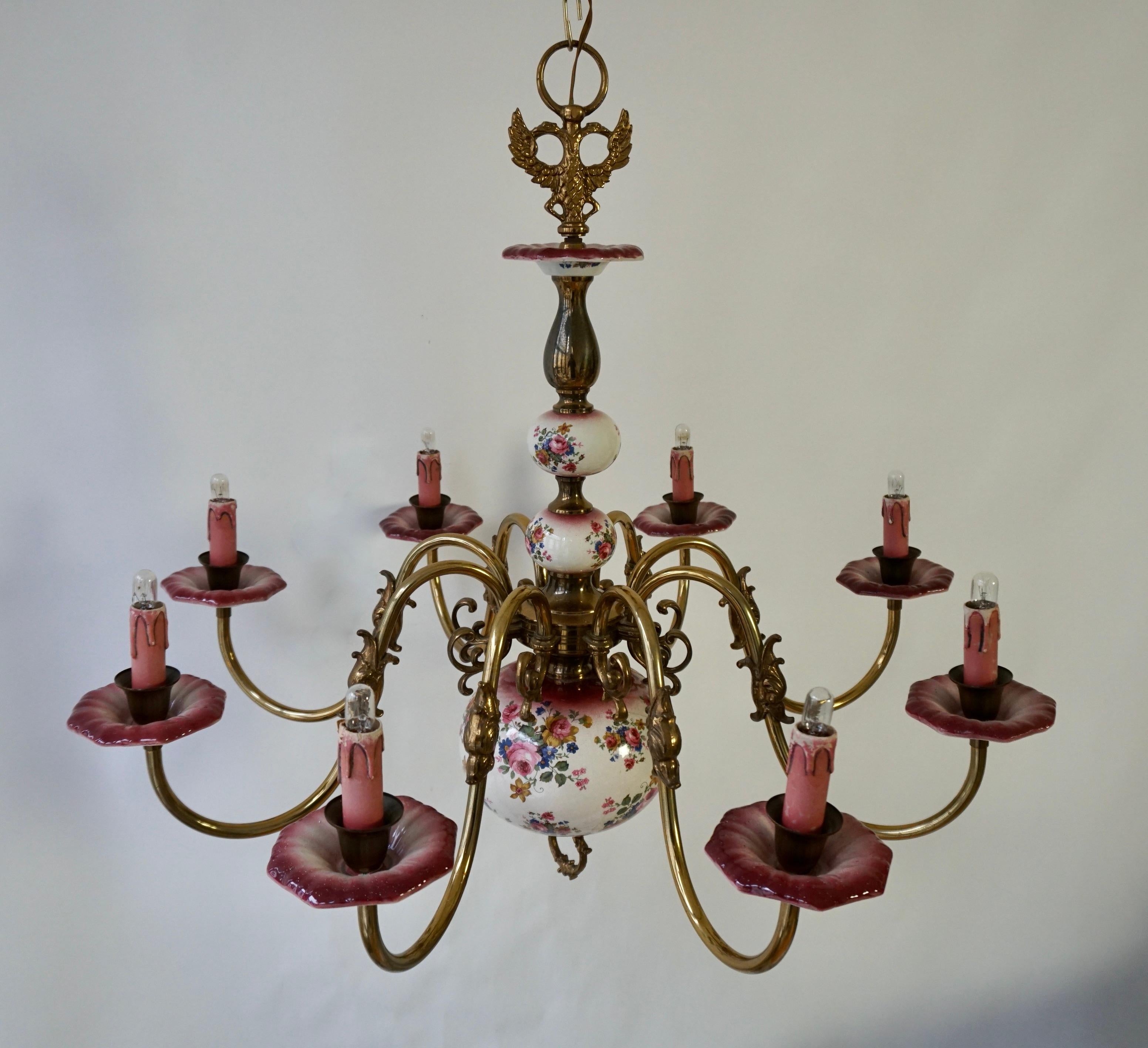 A large and detailed Delft chandelier with pinks and red.

A large Hollywood Regency eight-armed brass and porcelain chandelier from Holland manufactured in the mid-century (1960s and 1970s) decorated with flowers.

The lamp has eight sockets for