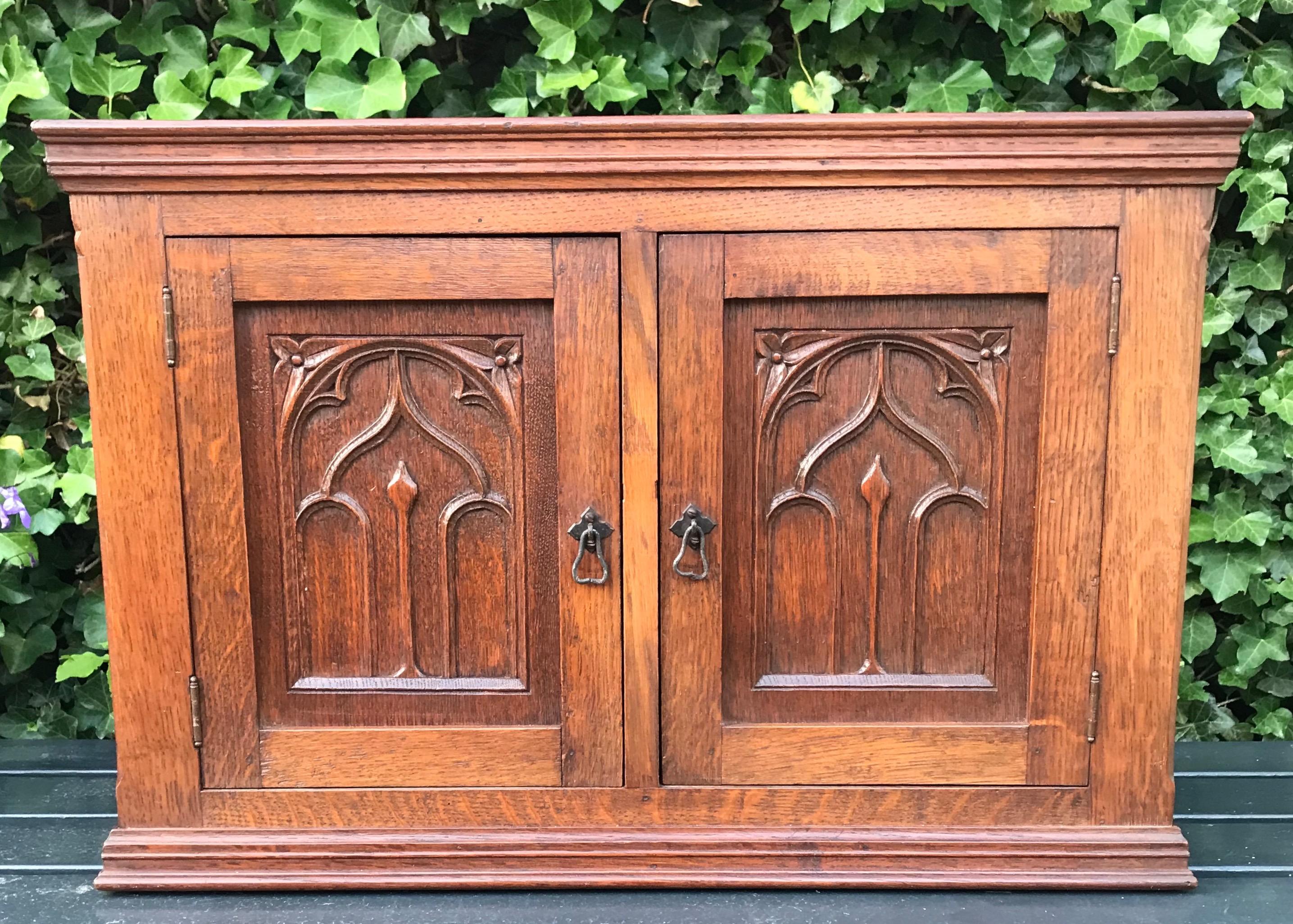 Small size and fine shape Gothic design wall cabinet with wonderful patina.

This early 20th century and well crafted cabinet can be used for all kinds of purposes. The gothic-art design motifs in the door panels are all hand-carved and an absolute