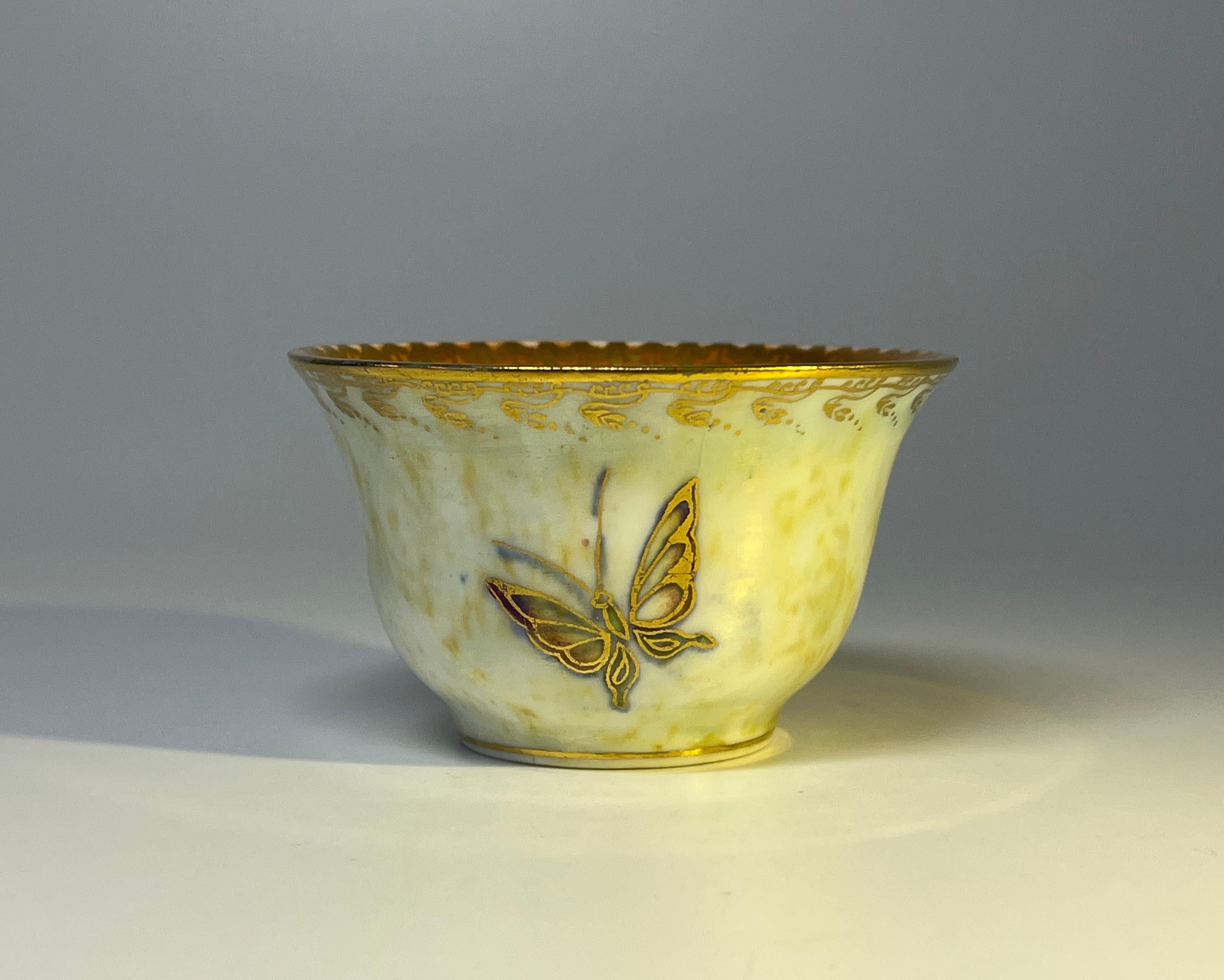 A glorious little bone china ordinary lustre bowl by Daisy Making-Jones for Wedgwood
Decorated on the outer with a trio of hand painted and gilded butterflies, on a ground of cream pearl lustre and gilded filigree rim.
The inner has a vivid orange