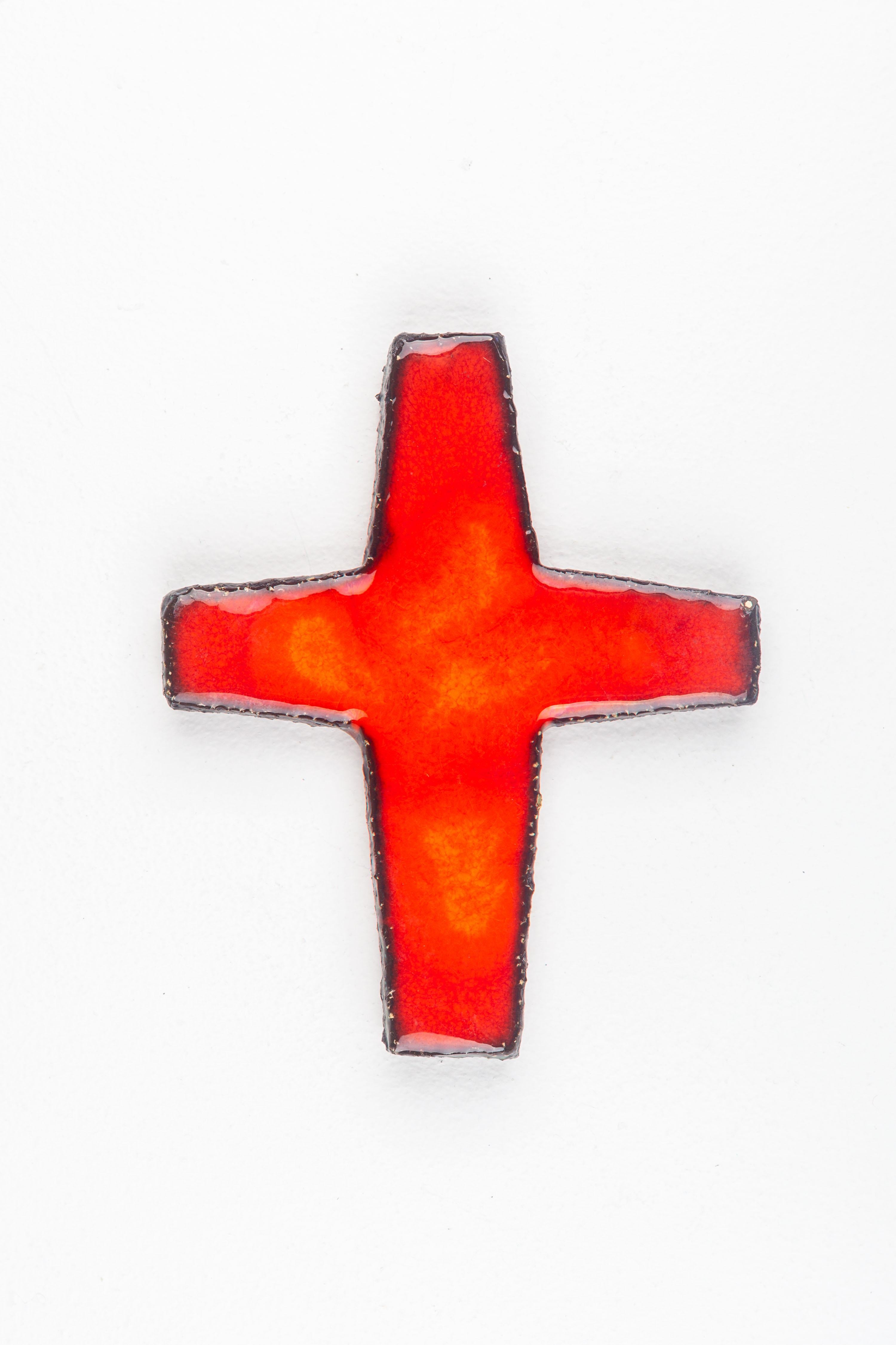 This mid-century modern wall cross represents the confluence of spiritual symbolism and the era's artistic innovation. Handcrafted by a European studio pottery artist, the piece features a vibrant, fiery red glaze, a bold choice that captures the