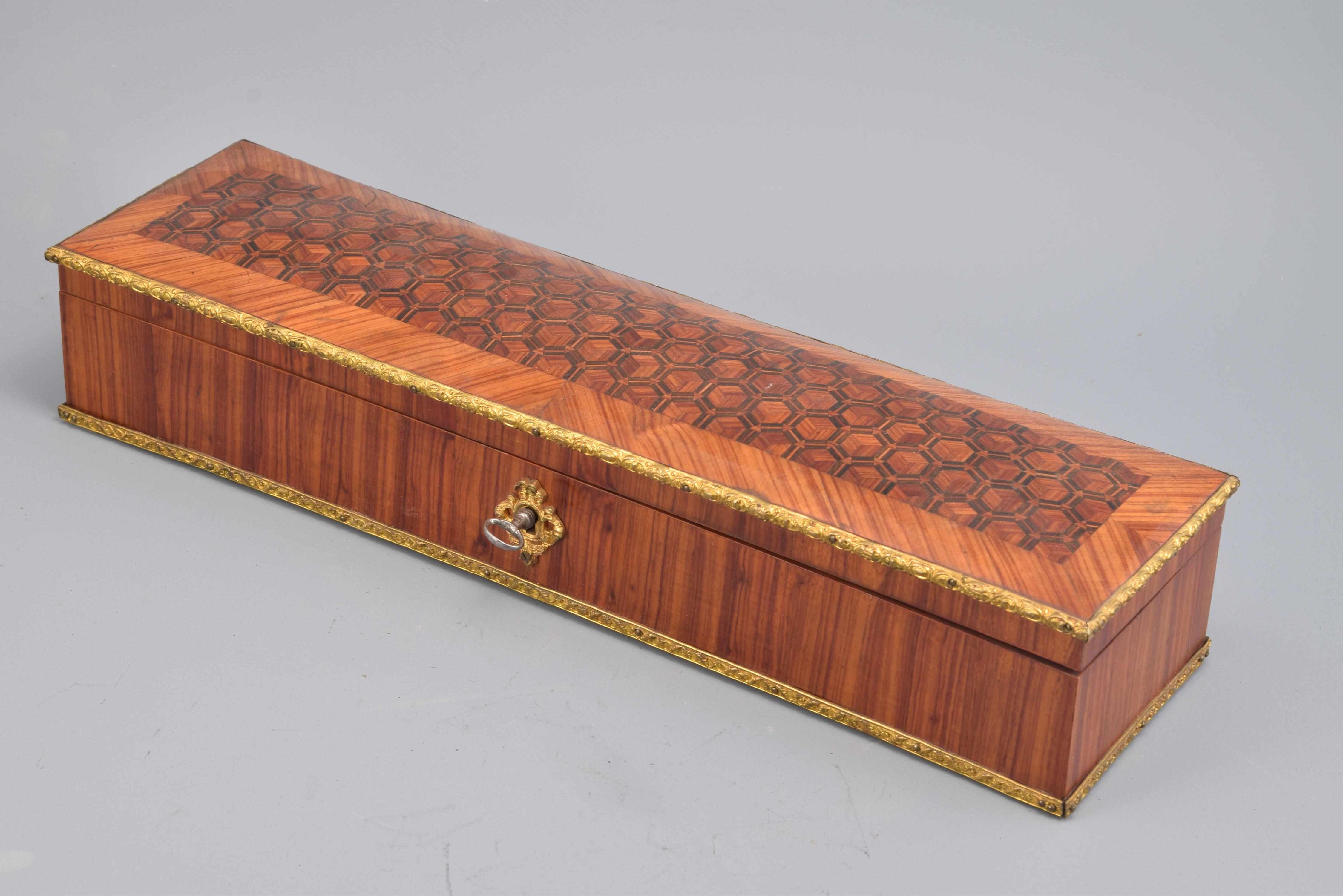 Box. Marquetry, rosewood, bronze, 19thcentury.
Rectangular box to store fans or gloves with the interior lined in light textile and exterior in wood and gilt bronze. It has a key closure on the front and a decoration on the lid of geometric