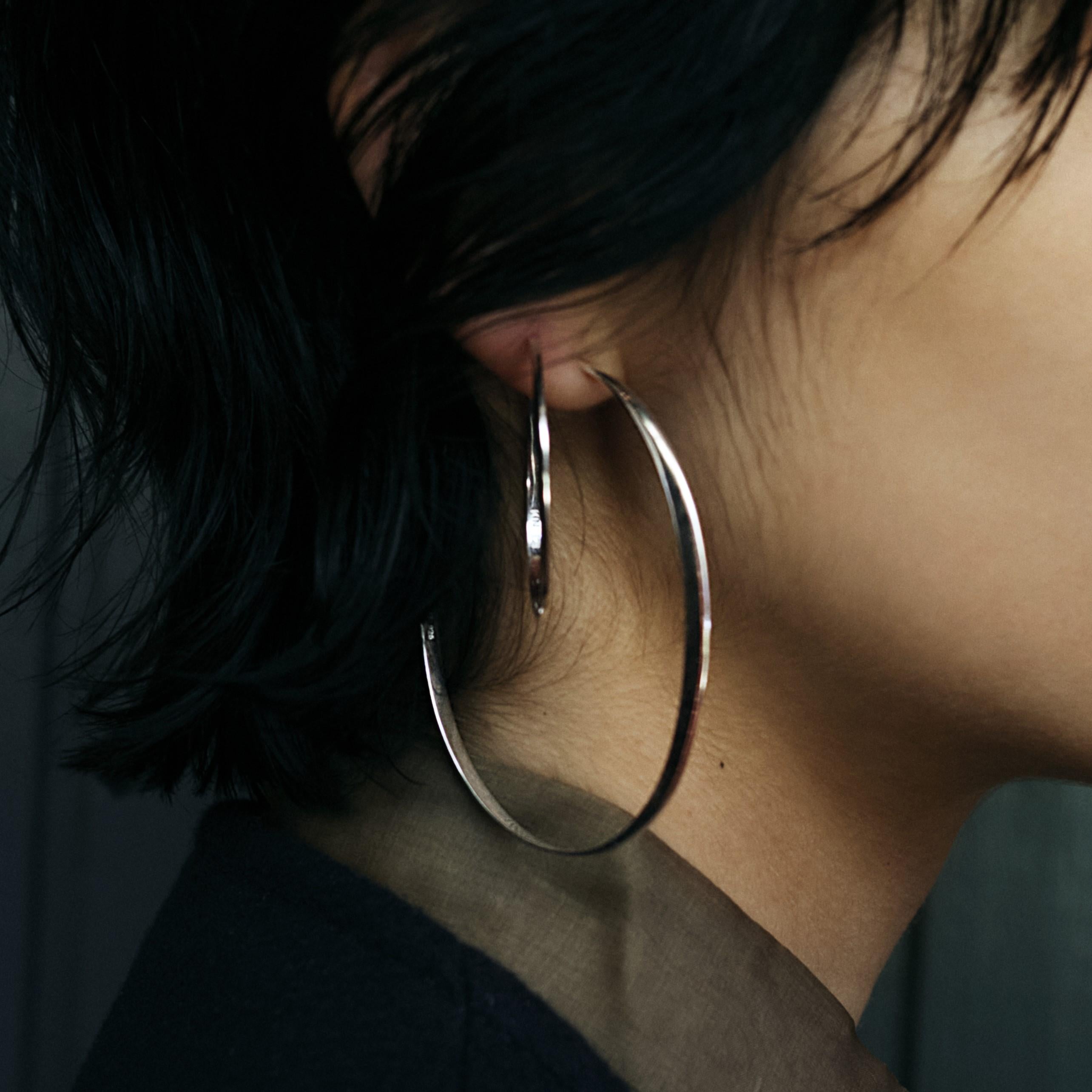 Also available in recycled 18k gold; as one piece earring, or in size medium and small.

A pair of the largest of our GLOW hoops. Handcrafted in solid recycled sterling silver, the twisted ellipse will catch and reflect the light as you move.

To Be