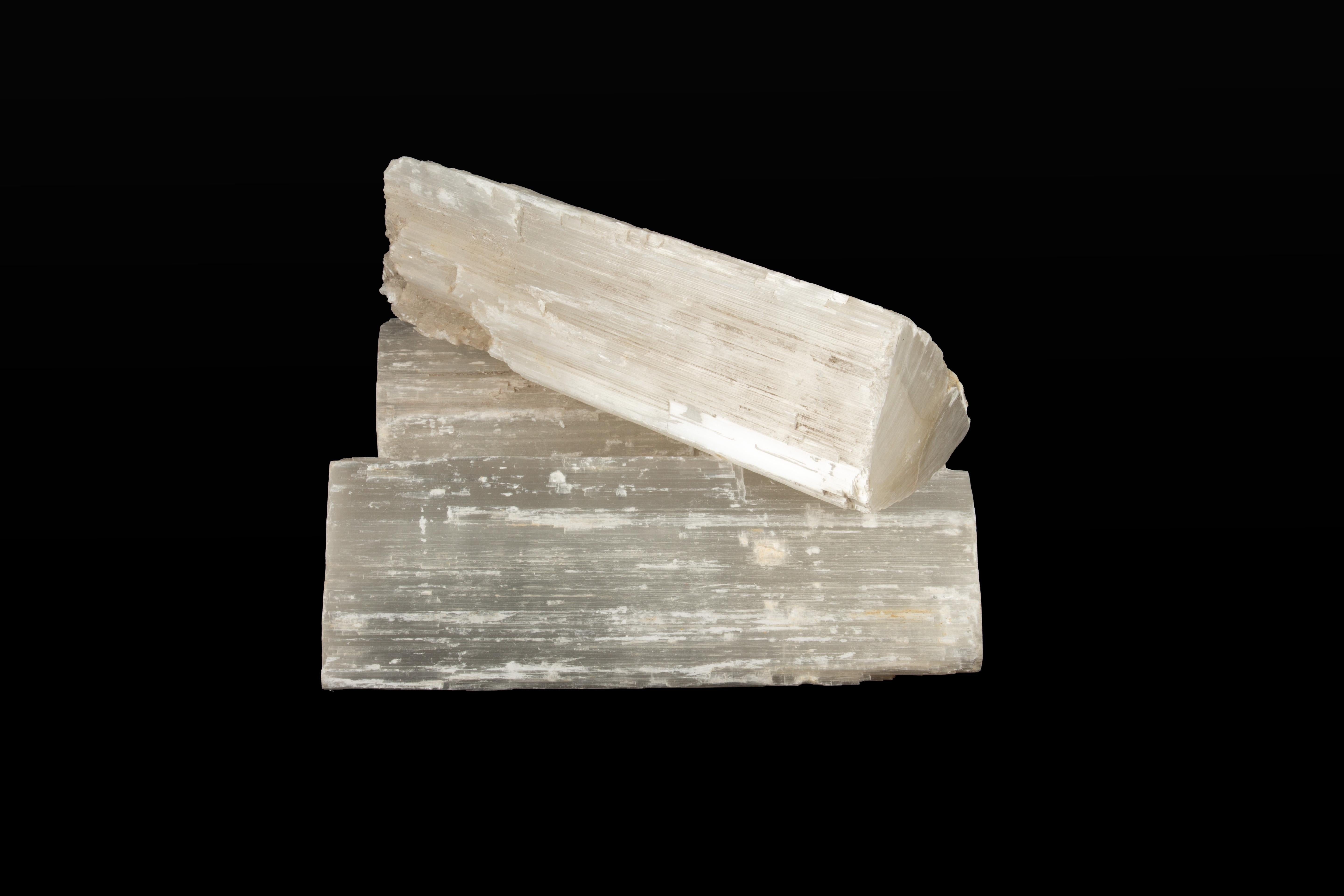 Set of Three Selenite Logs. These striking selenite logs are intricately carved to mimic the appearance of natural cut wood, while showcasing the luminous and striated beauty characteristic of selenite. Sourced from the Atlas Mountains in Morocco,