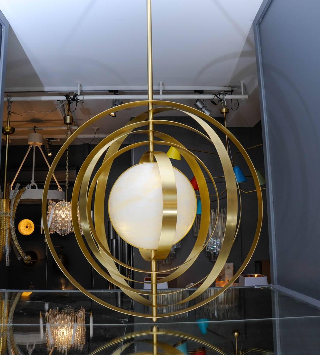 New design by Glustin Luminaires, massive alabaster globe suspension with six brass rings gravitating around it. Each ring is independent and can be placed however you'd like.