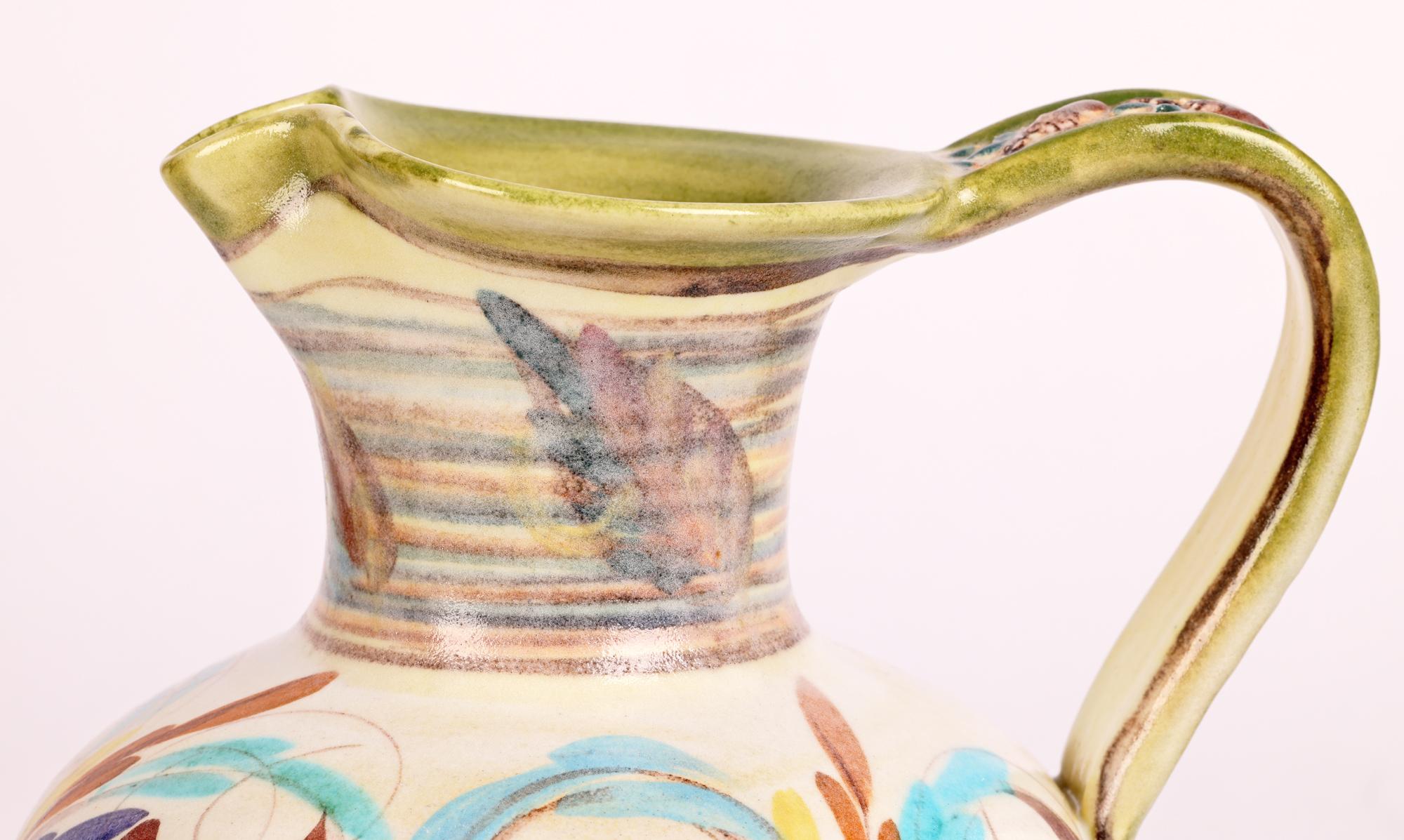 Une élégante cruche à anse Denby en poterie d'art du milieu du siècle, peinte à la main de motifs floraux stylisés par le célèbre céramiste anglais Glyn Colledge (britannique, 1922-2000). 

Glyn Colledge a commencé à travailler chez Denby tout en
