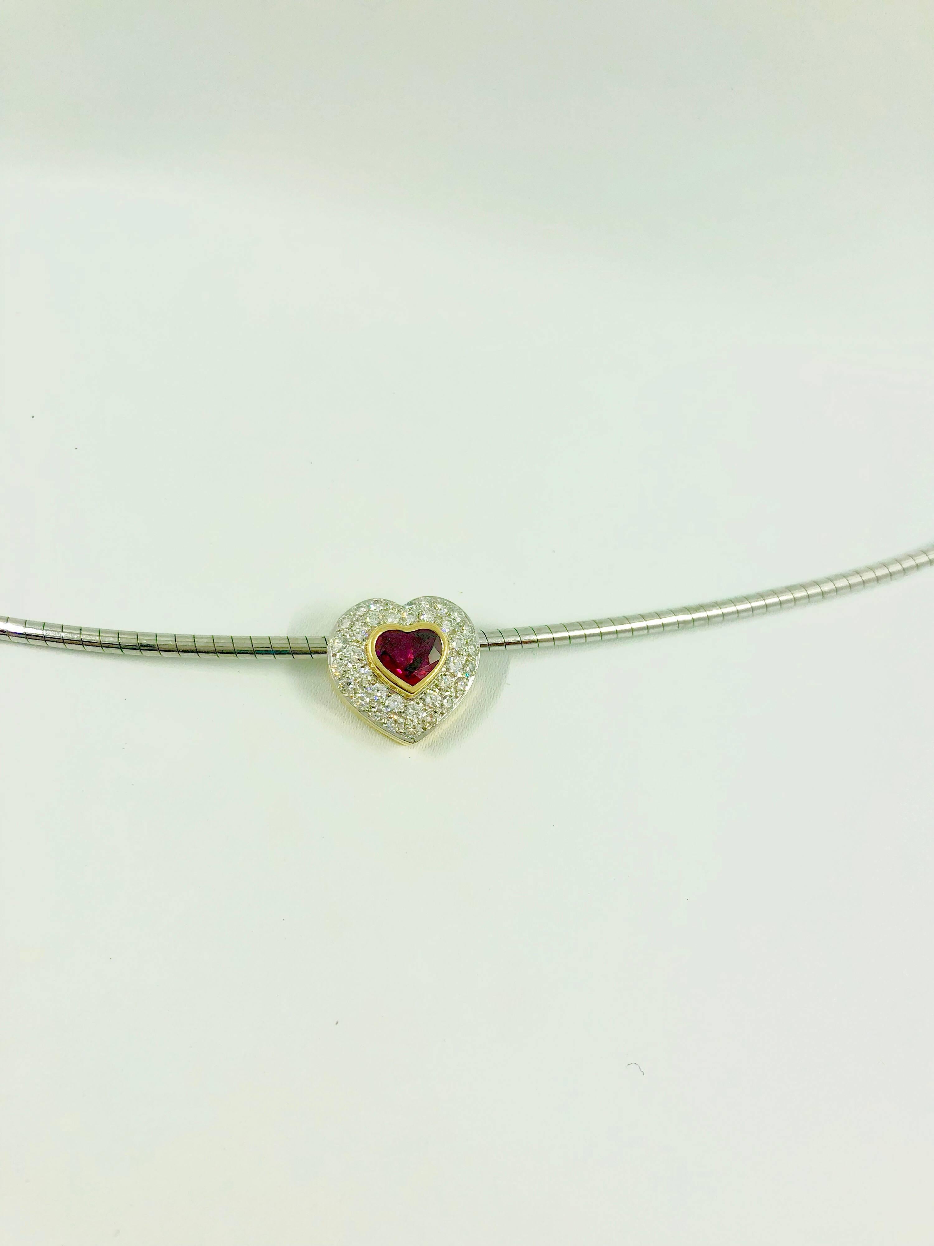 A G.MINNER white and yellow gold clip pendant set with a beautiful heart-shaped Burmese ruby surrounded by 35 brilliant cut diamonds. The pendant is a unique creation entirely handmade.
The color of this stone is described in the trade under the