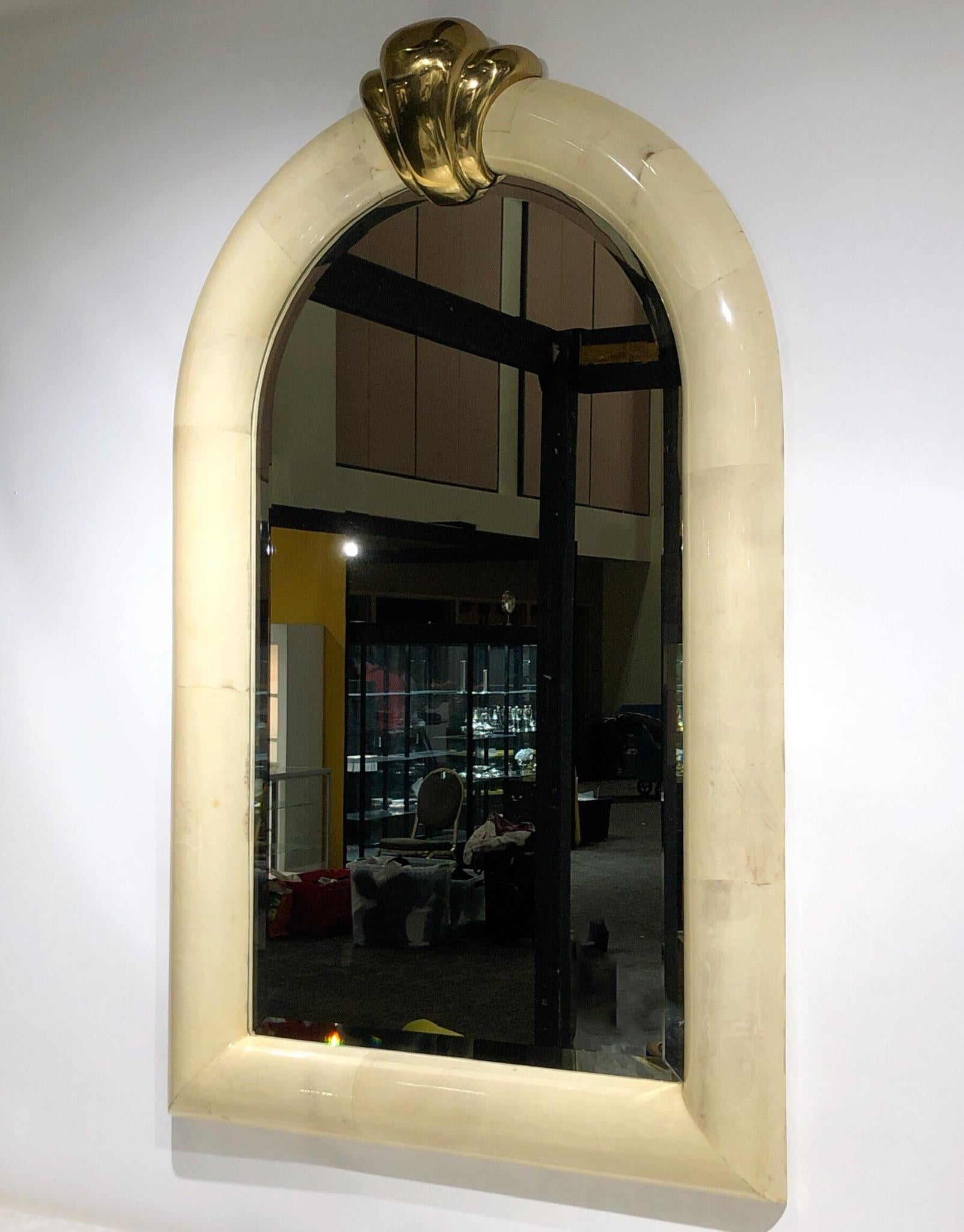 A glamorous 1980s goatskin and brass wall mirror in the manner of Karl Springer. The frame is constructed of wood covered with goatskin and then clear lacquered the keystone is solid brass.
Overall dimension: 58” high 36”wide 5” deep.