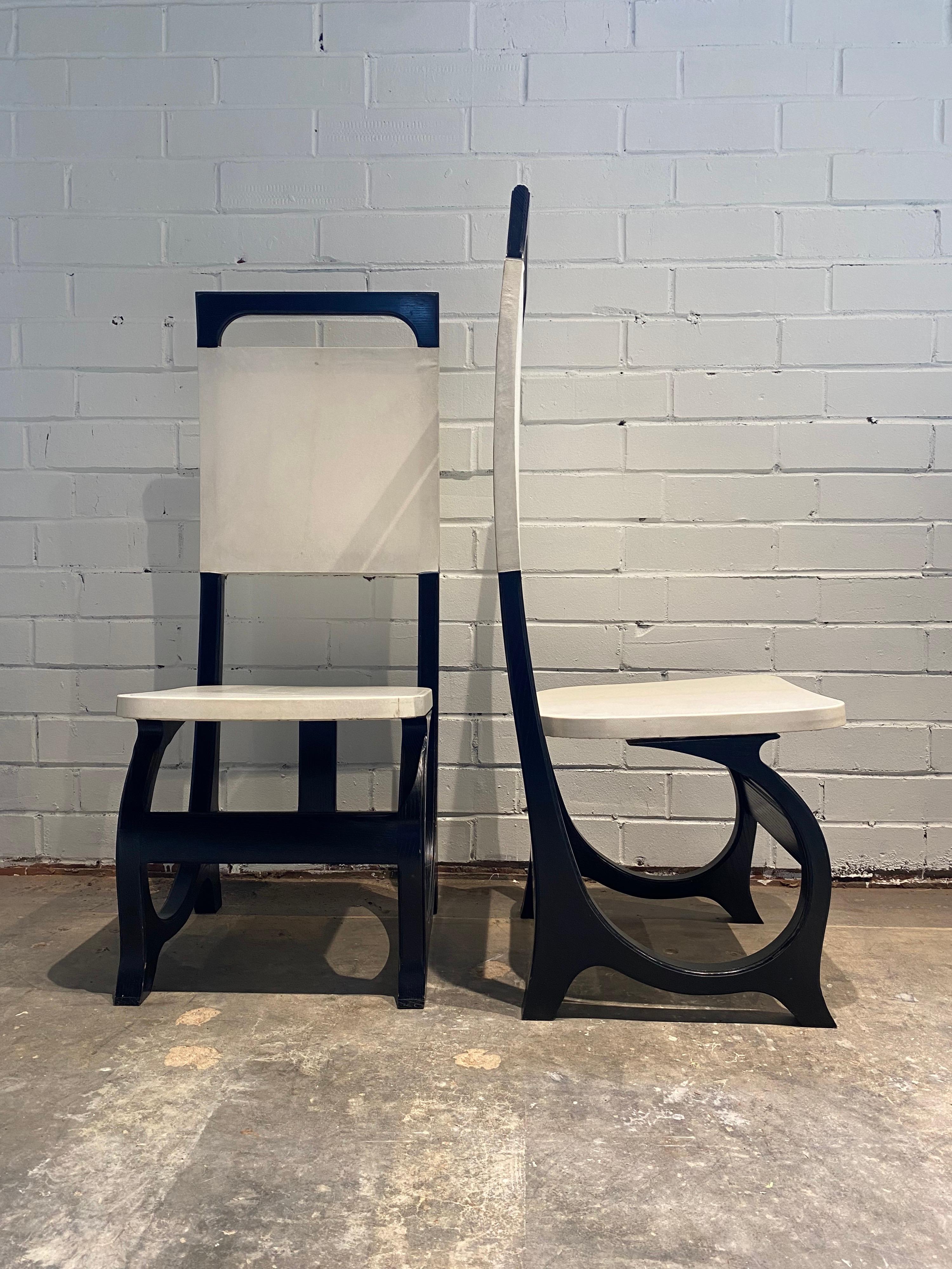 An interesting pair of sculpted oak chairs with goatskin parchment seats and back. These have a very striking look with a design that have both an Art Nouveau and mid century modern vibe. In the style of Carlo Bugatti the chairs offer a unique