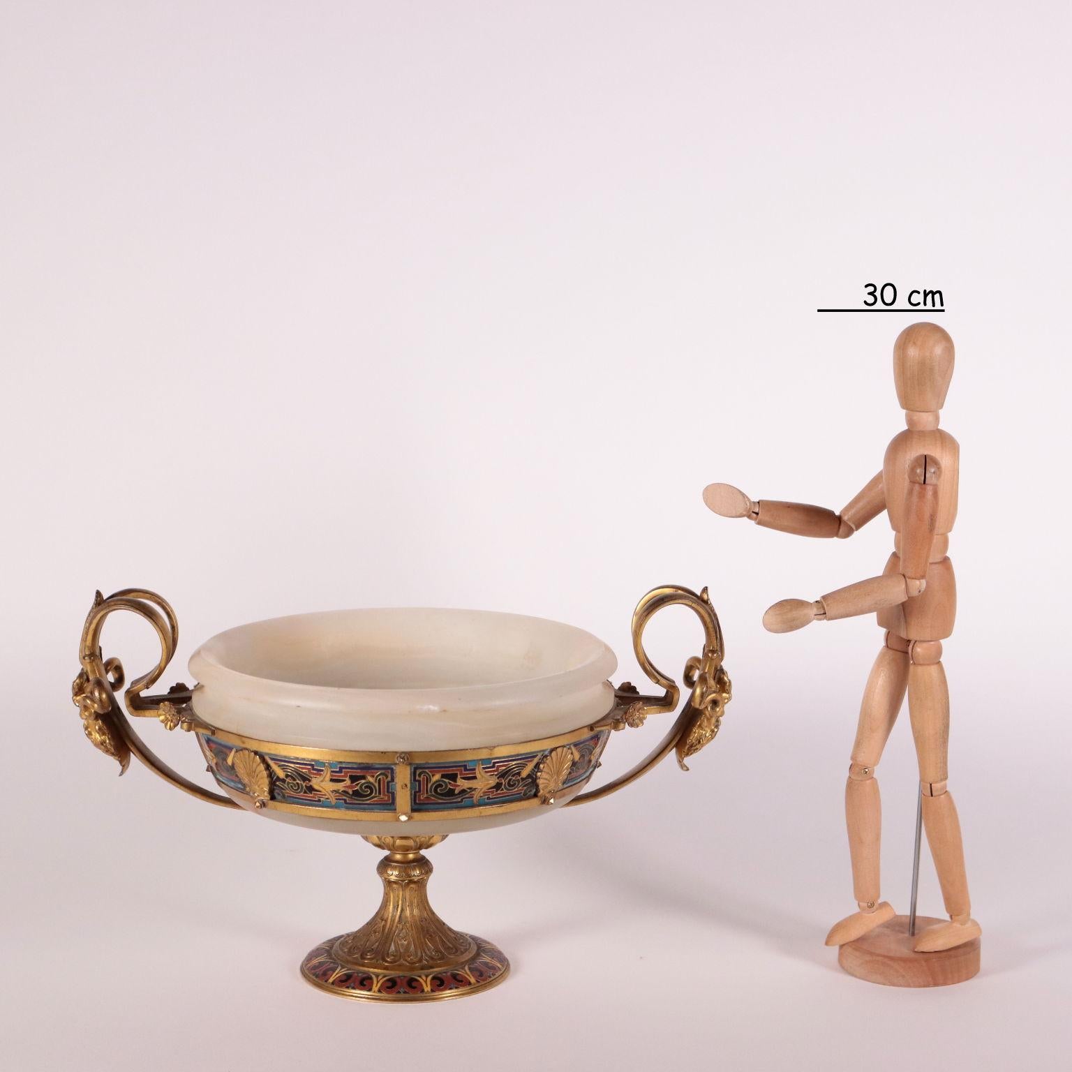 Alabaster goblet held by a gilded bronze support with an enameled decoration realized with the champleve technique. The base is shaped as an upside down goblet and holds a circular bronze structure with enameled vegetal themed decorations. Handles