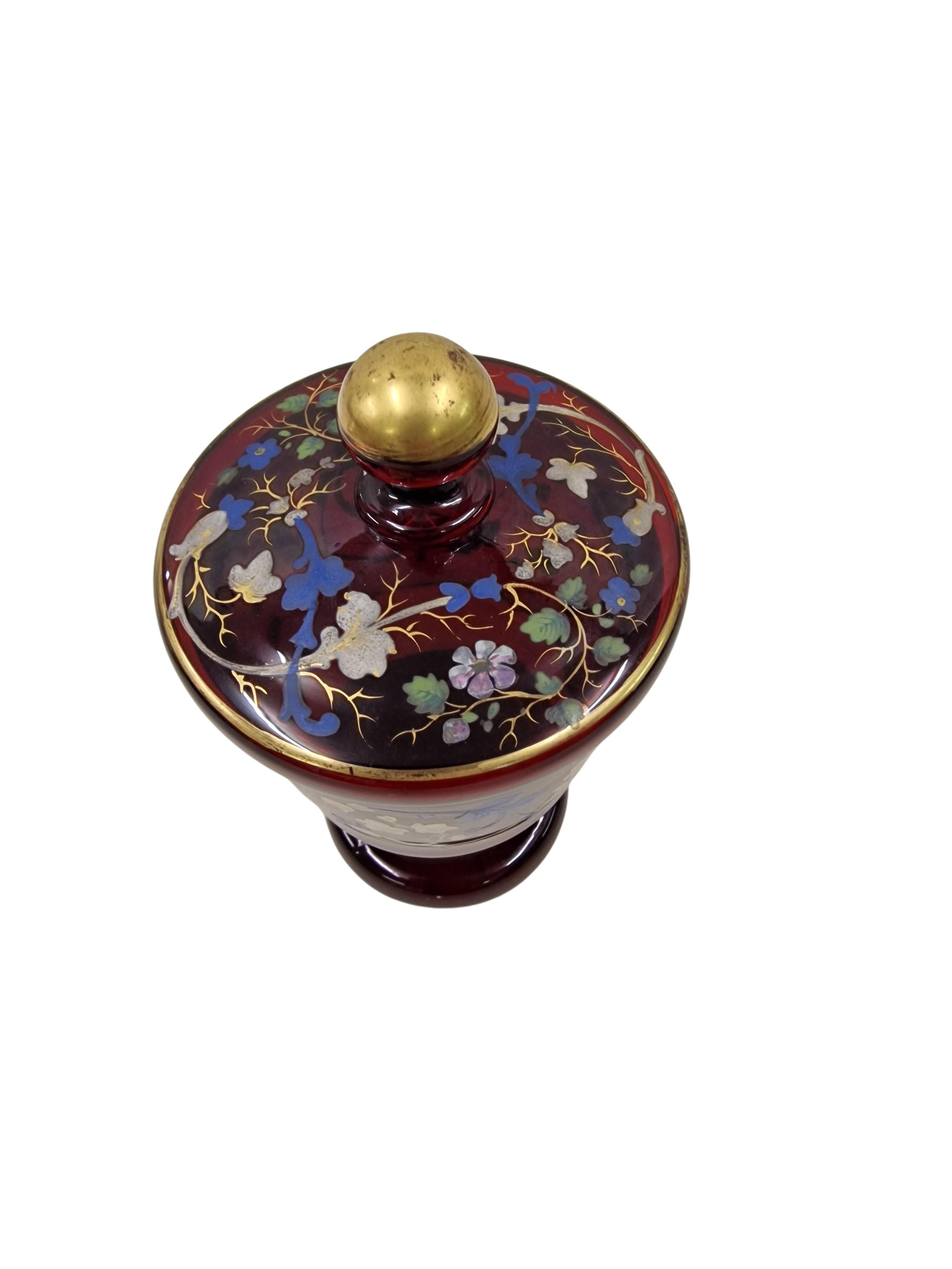 Wunderschöner Pokal mit Deckel, hergestellt um 1850 in der späten Biedermeierzeit in Mitteleuropa, in Österreich. Dieses wunderbare Objekt ist aus rubinrotem Glas, das im Licht eine schöne Färbung aufweist. Der Kelch ist mit handgemalten,