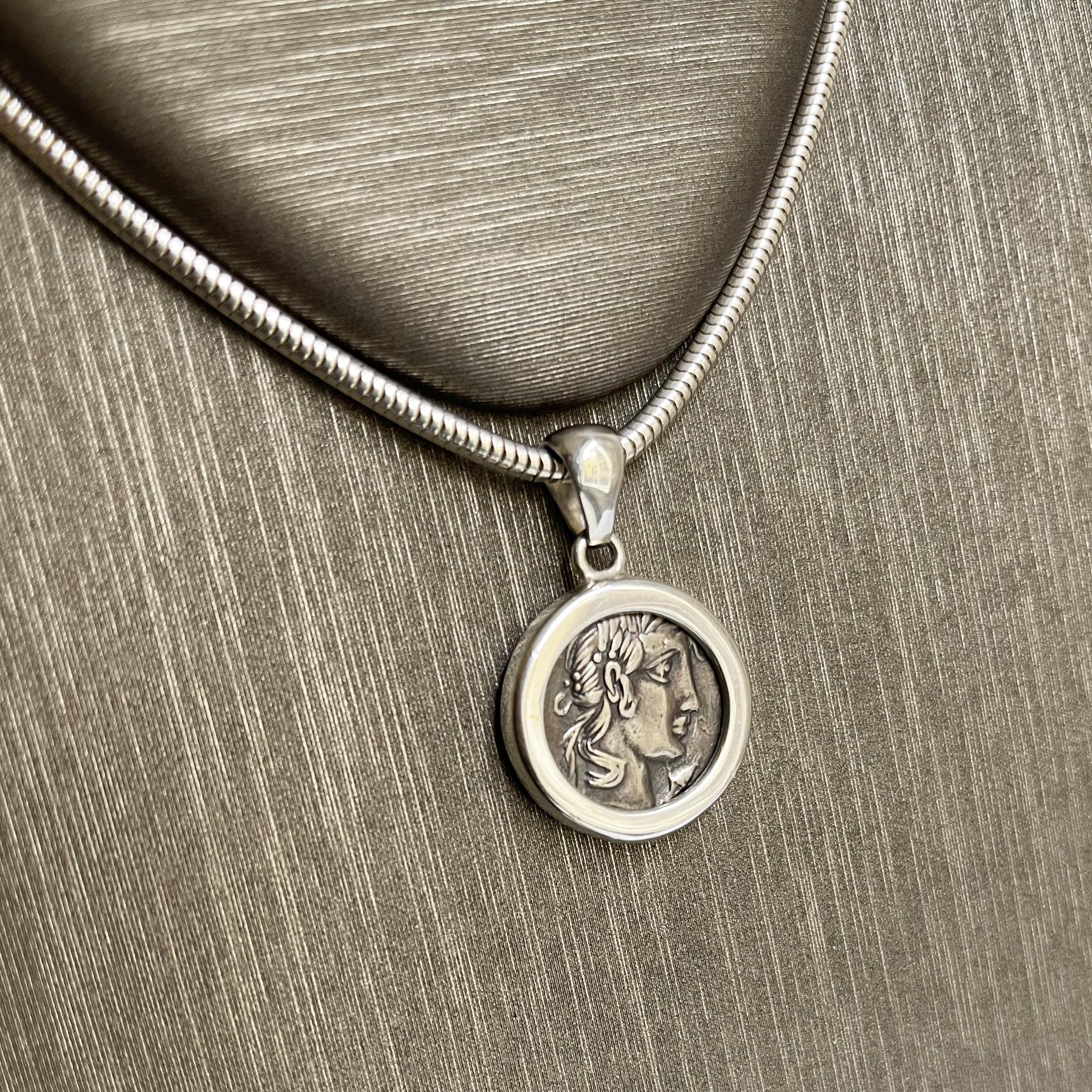 This sterling silver pendant has been set with an authentic 1st century BC Roman coin depicting the god Apollo. The contemporary setting was made by our goldsmiths. The silver coin, set in the center, authentic Roman, was minted in 48 BC by Vibio