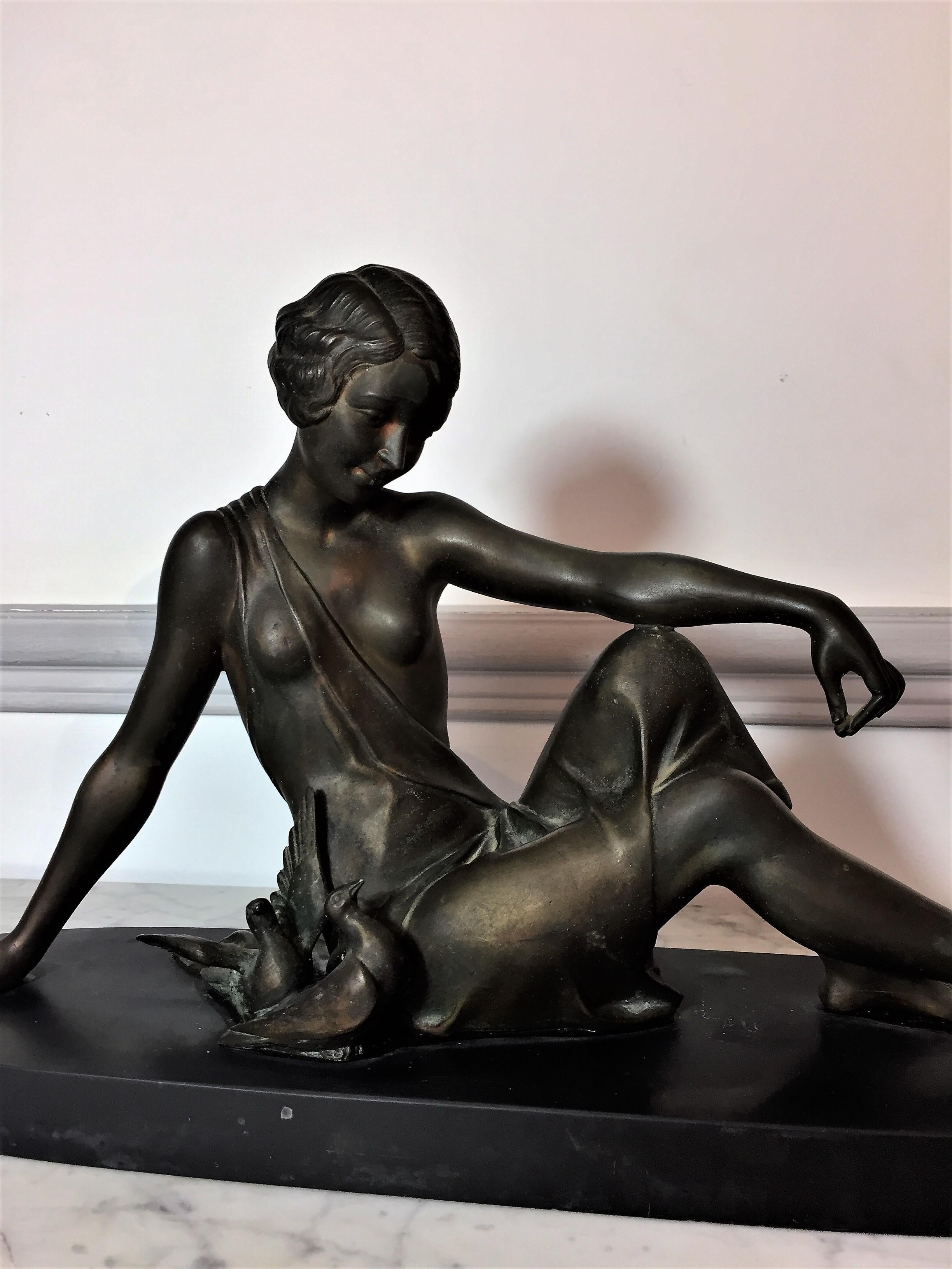 Par Armand Godard, belle sculpture à belle patine d'époque Art Déco représentant une femme assise nourrissant des oiseaux sur terrasse ovale en marbre noir, 
France, 
vers 1930

Armand Godard a réalisé de nombreuses statuettes chryséléphantines en