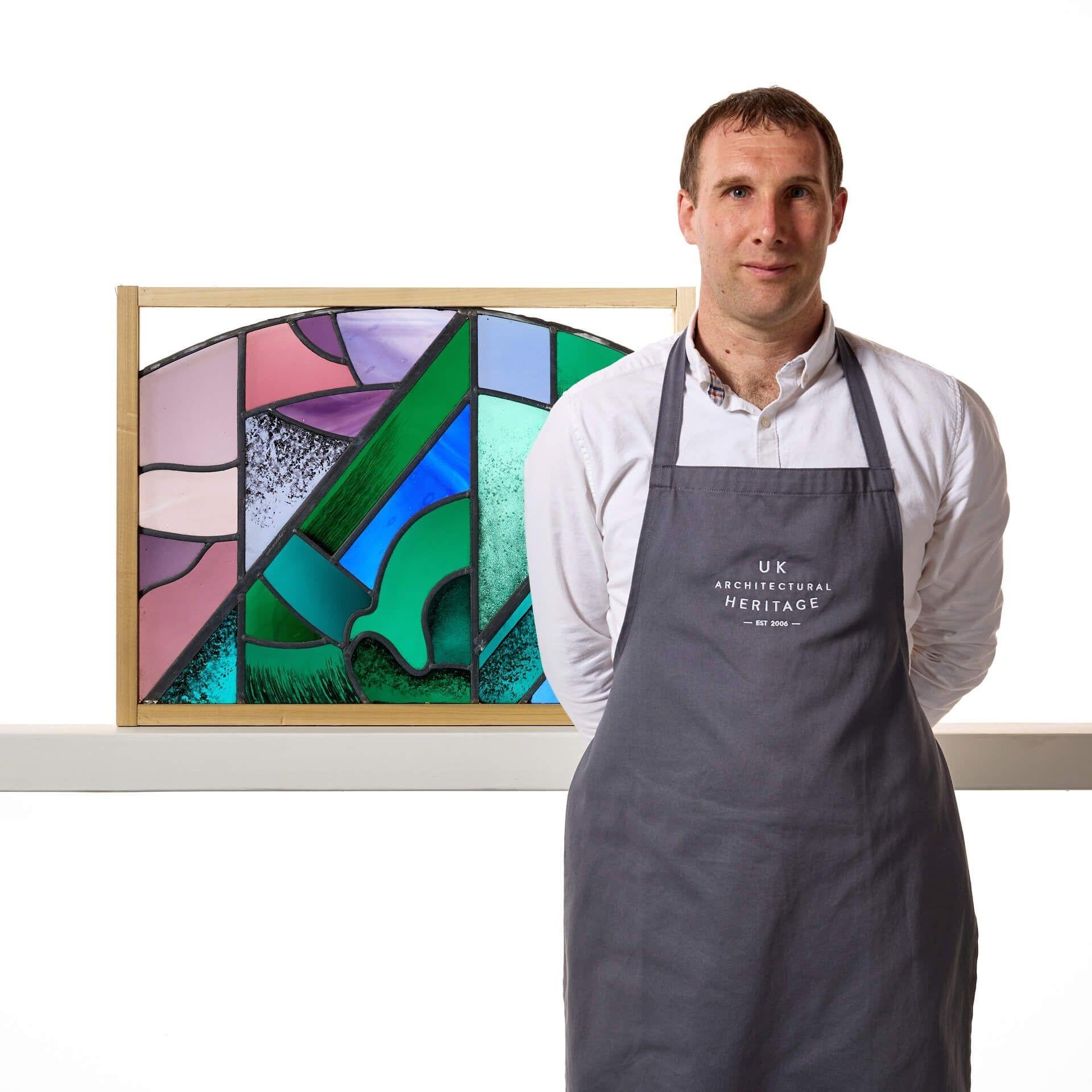 A Goddard and Gibbs abstract style stained glass panel with a shallow arch.

This is an abstract modernist stained glass panel with an unusual design, blending together a range of vibrant colours of greens, blues and pinks, as well as shapes and