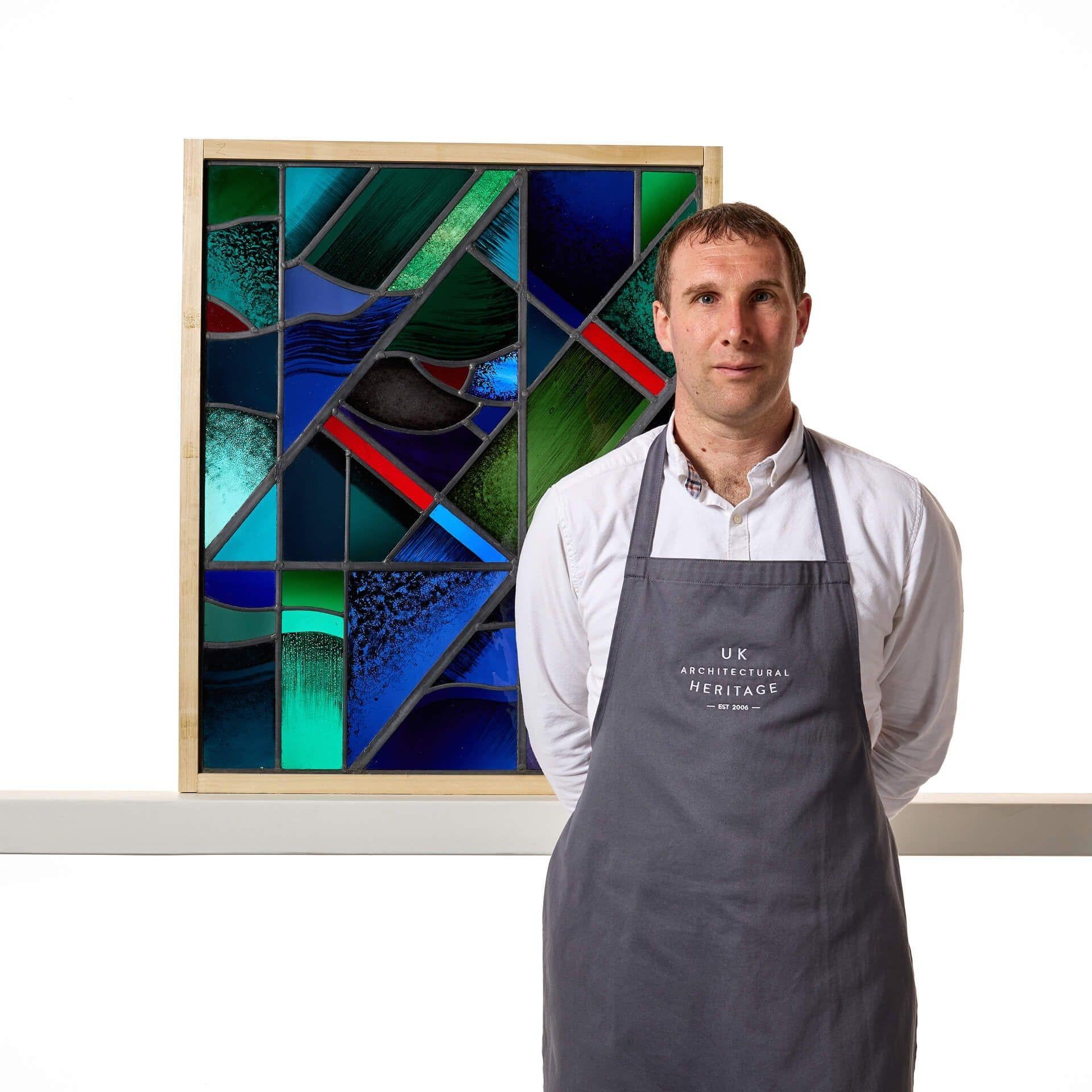 Un grand panneau de vitrail géométrique, de style moderniste, réalisé par les célèbres vitraillistes Goddard et Gibbs.

Il s'agit d'un vitrail abstrait d'un style moderne inhabituel, mêlant une gamme de couleurs vives, telles que les pourpres, les