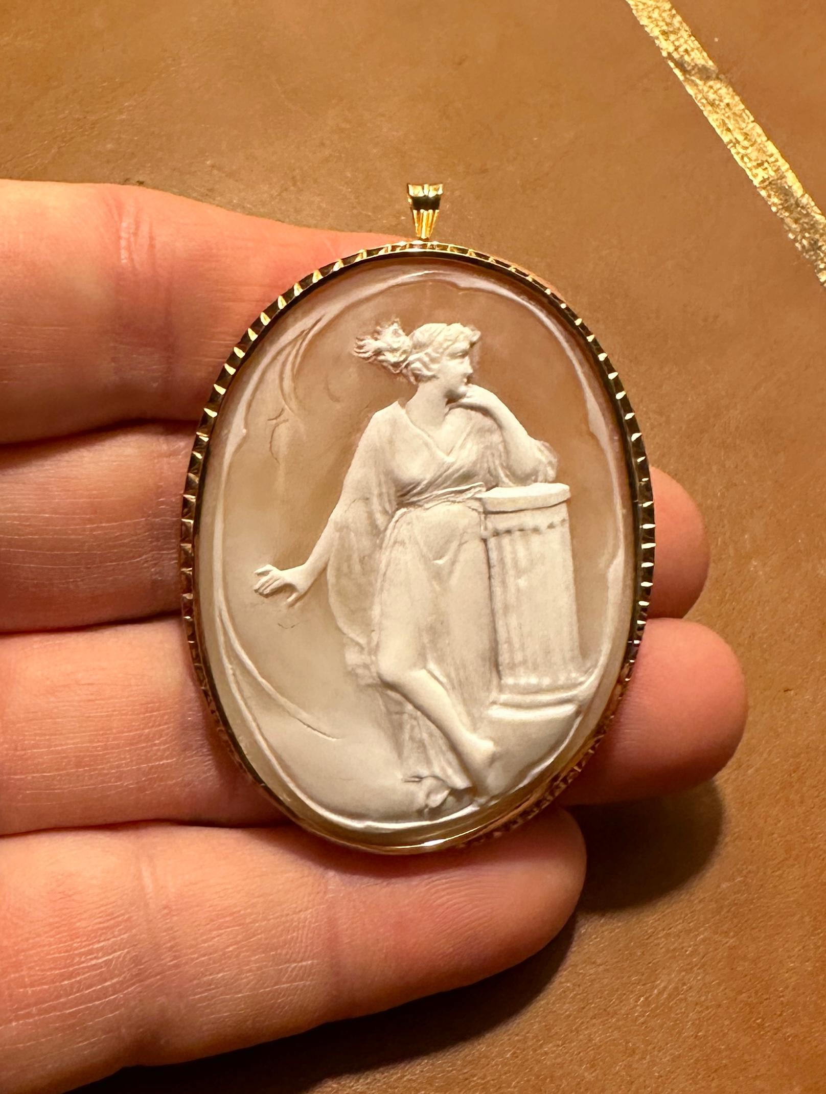 This is an absolutely stunning and very rare large antique Shell Cameo Pendant Brooch with a hand carved image of a Goddess Maiden standing by a Greek or Roman Column!  The cameo is set in 18 Karat Yellow Gold and has a bale to be worn as a necklace