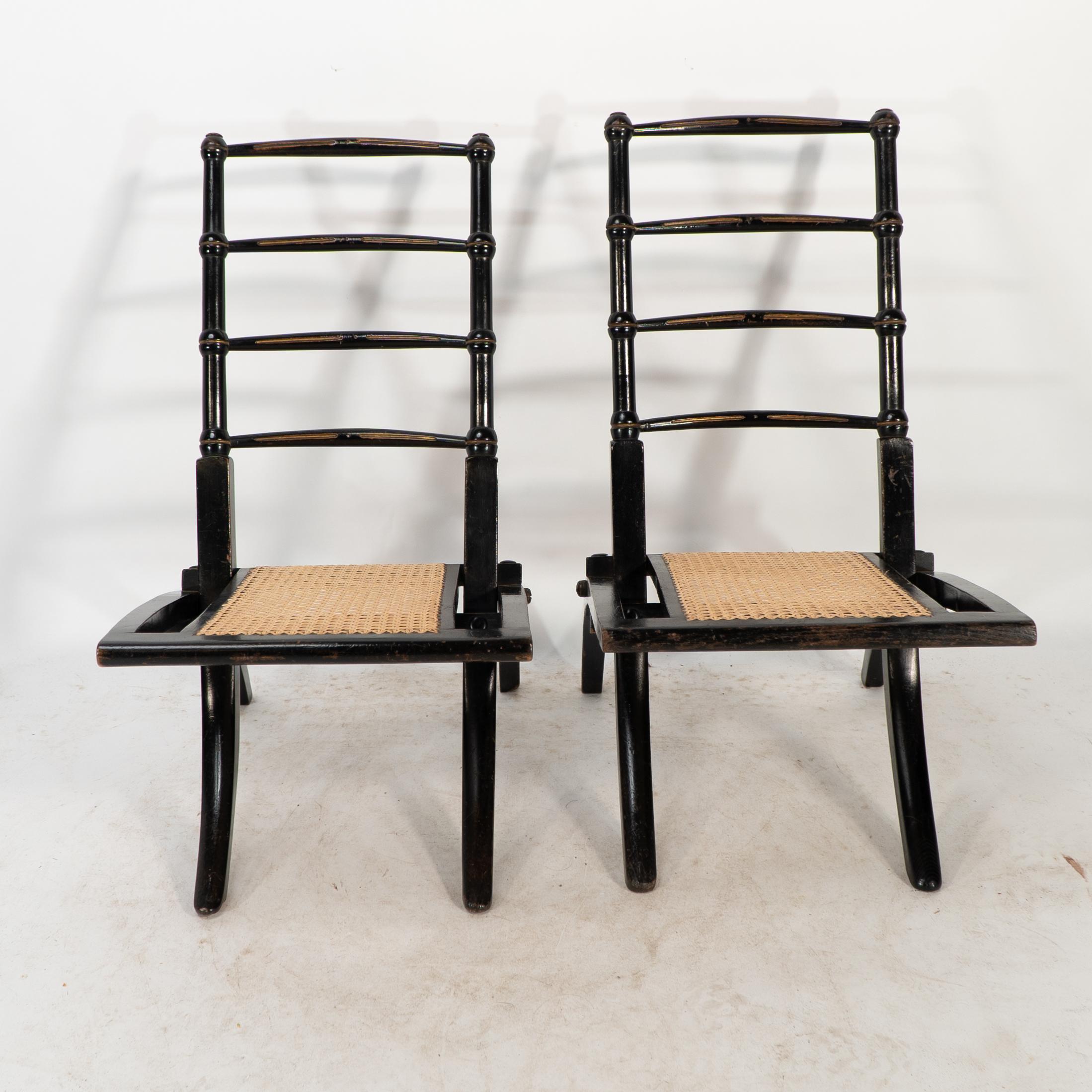 EW Godwin Style de. Paire de chaises pliantes ébonisées du Mouvement Esthétique, dont le dossier est orné de fuseaux et dont l'assise est en rotin neuf. Cette offre concerne la paire (2 chaises). Nous disposons également d'une pièce unique pour