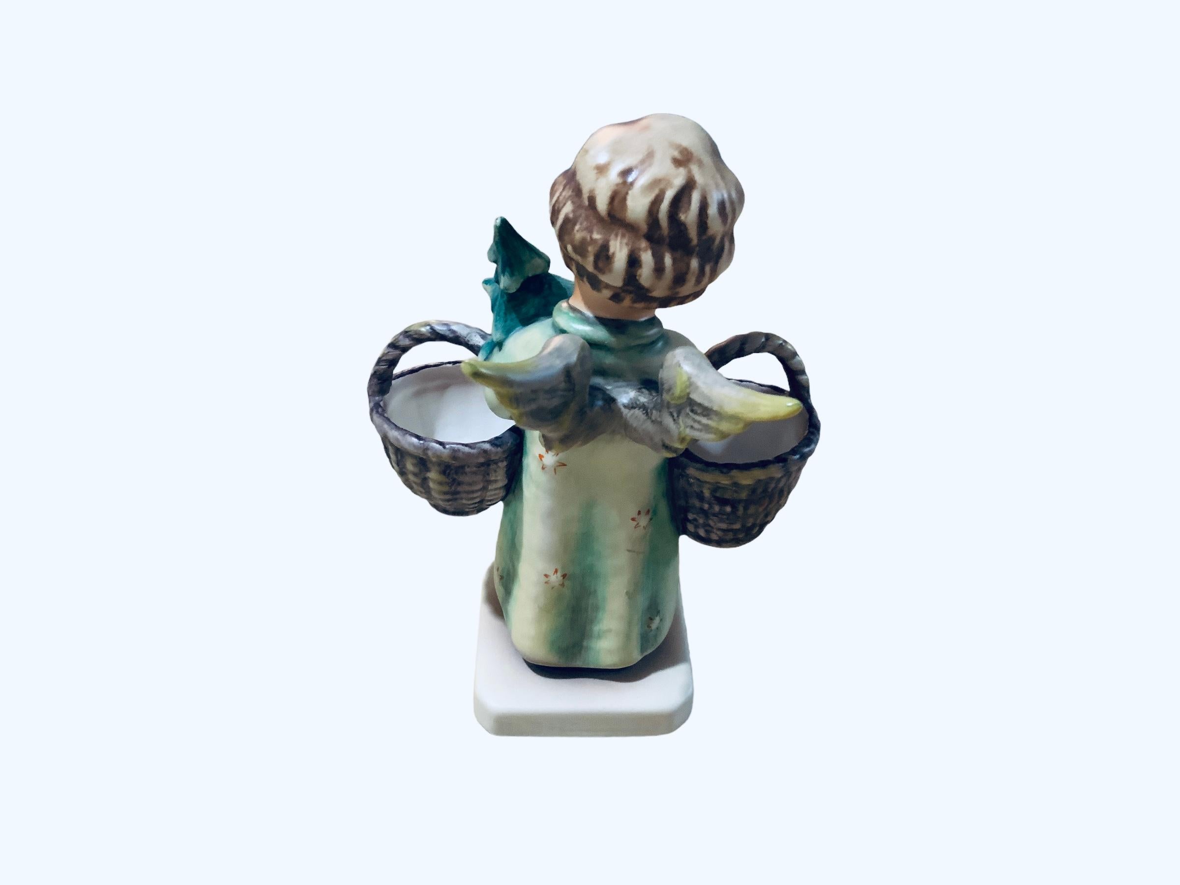 This is a Hummel porcelain figurine of an angel. It’s named “Christmas Angel”. Its mark is TMK 7 (1991-99). The trademark of Goebel company is below the base.