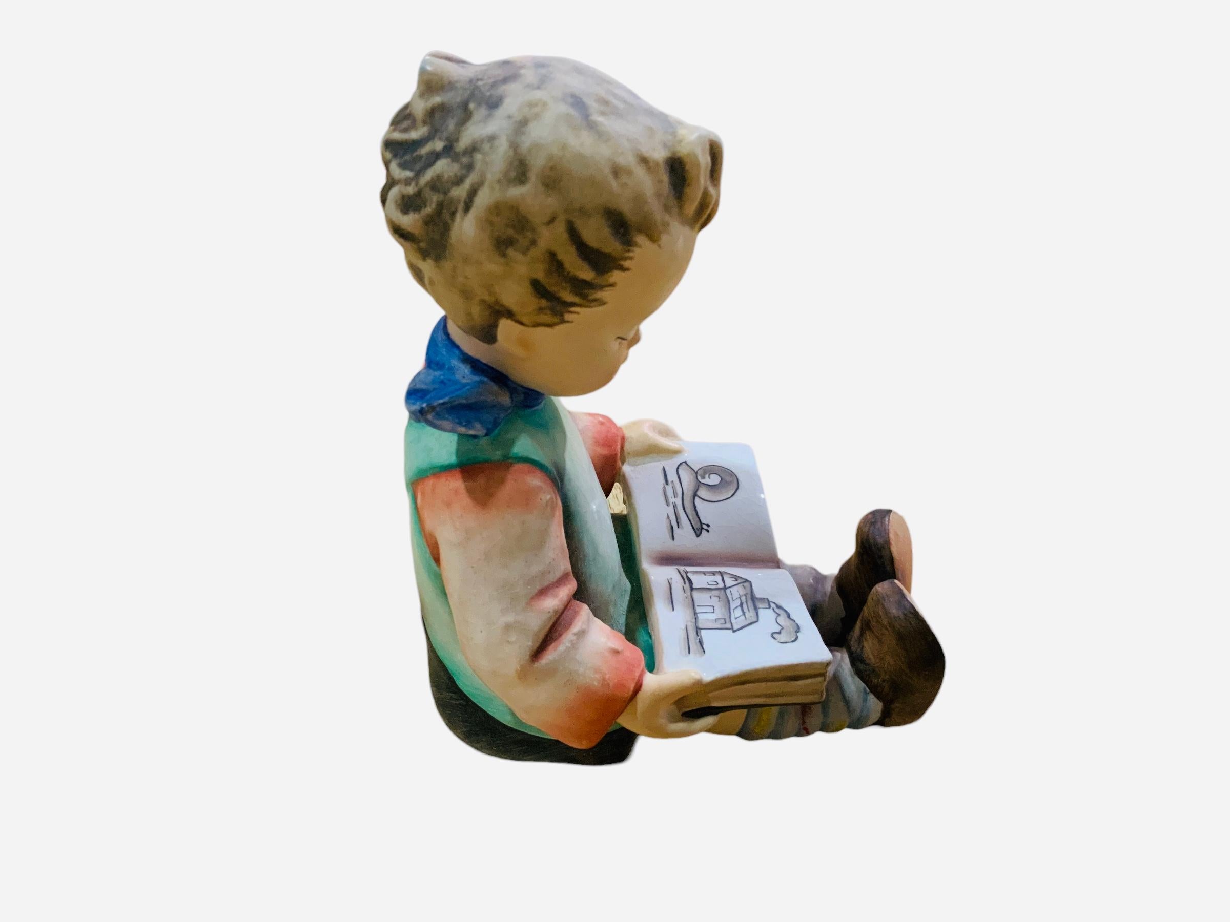 This is a Hummel porcelain figurine boy . It’s named “Reading Boy”. Its mark is TMK6 (1979-1991). The trademark of Goebel company is below the base.