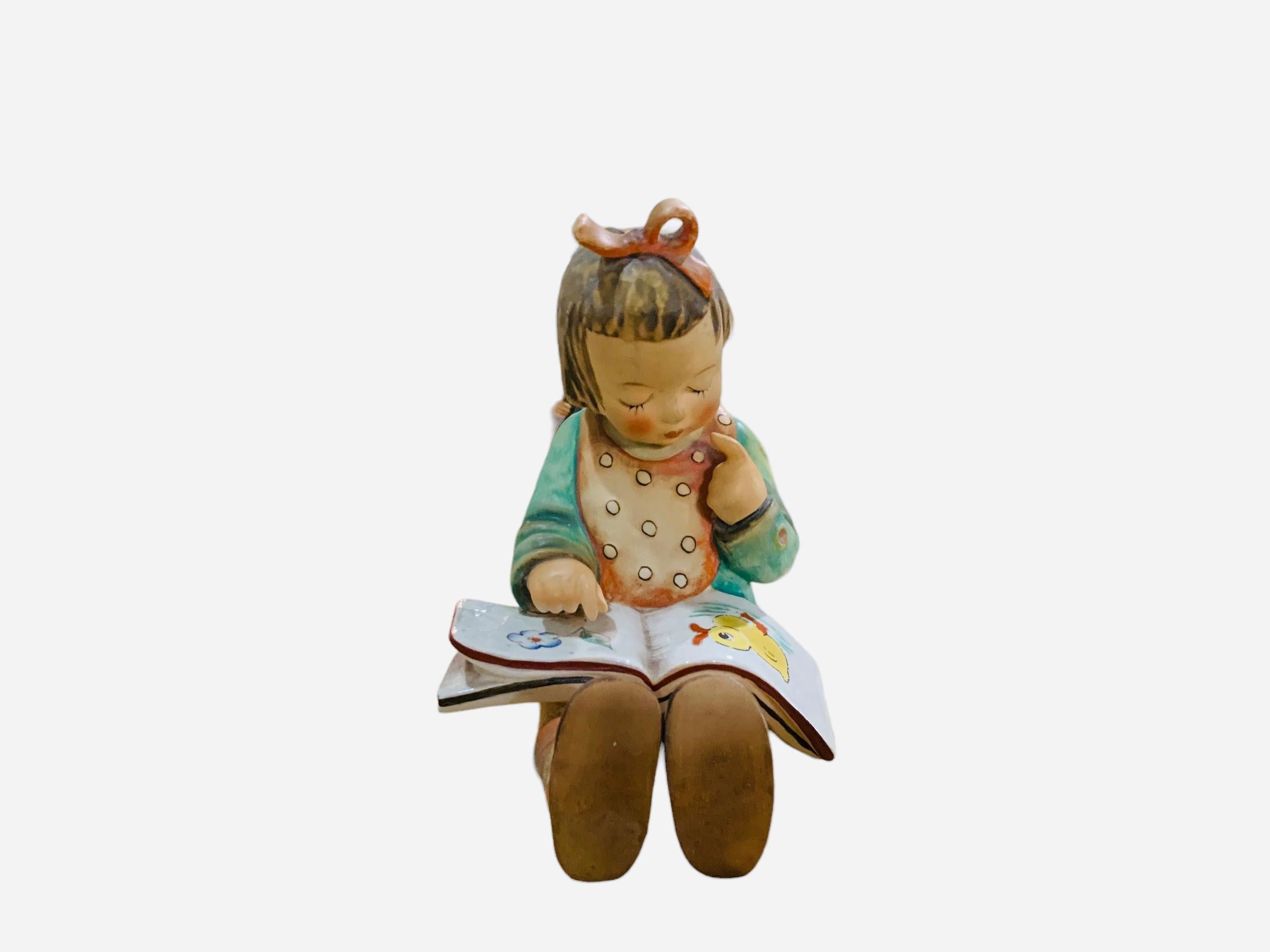 This is a Hummel porcelain figurine girl . It’s named “Reading Girl”. Its mark is TMK5 (1970’s). The trademark of Goebel company is below the base.