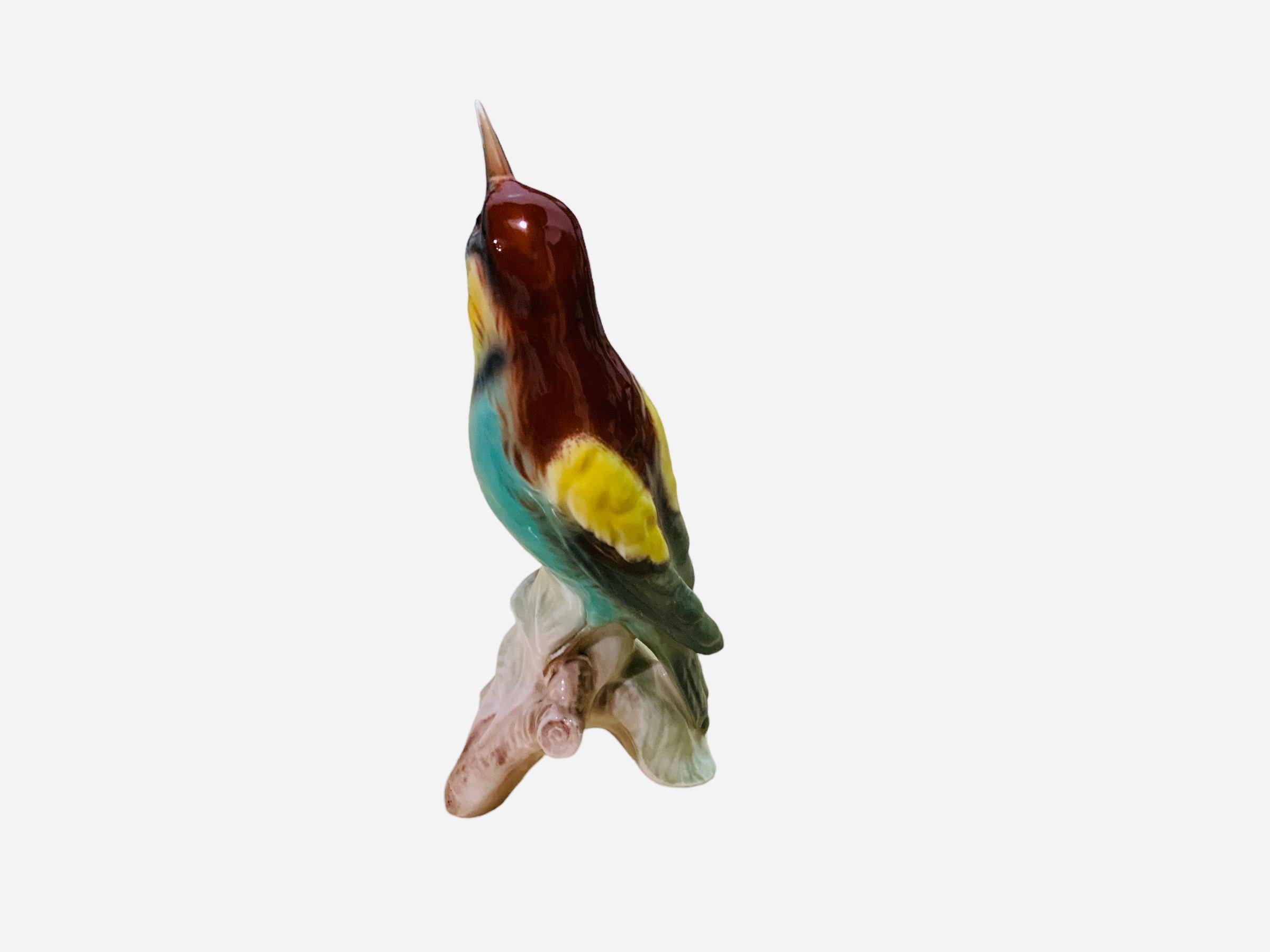 This is a Goebel porcelain figurine of a bird. It depicts a very well done hand painted Bee Eater. It is standing up over a branch with few leaves. It is hallmarked Goebel, Germany at the base.