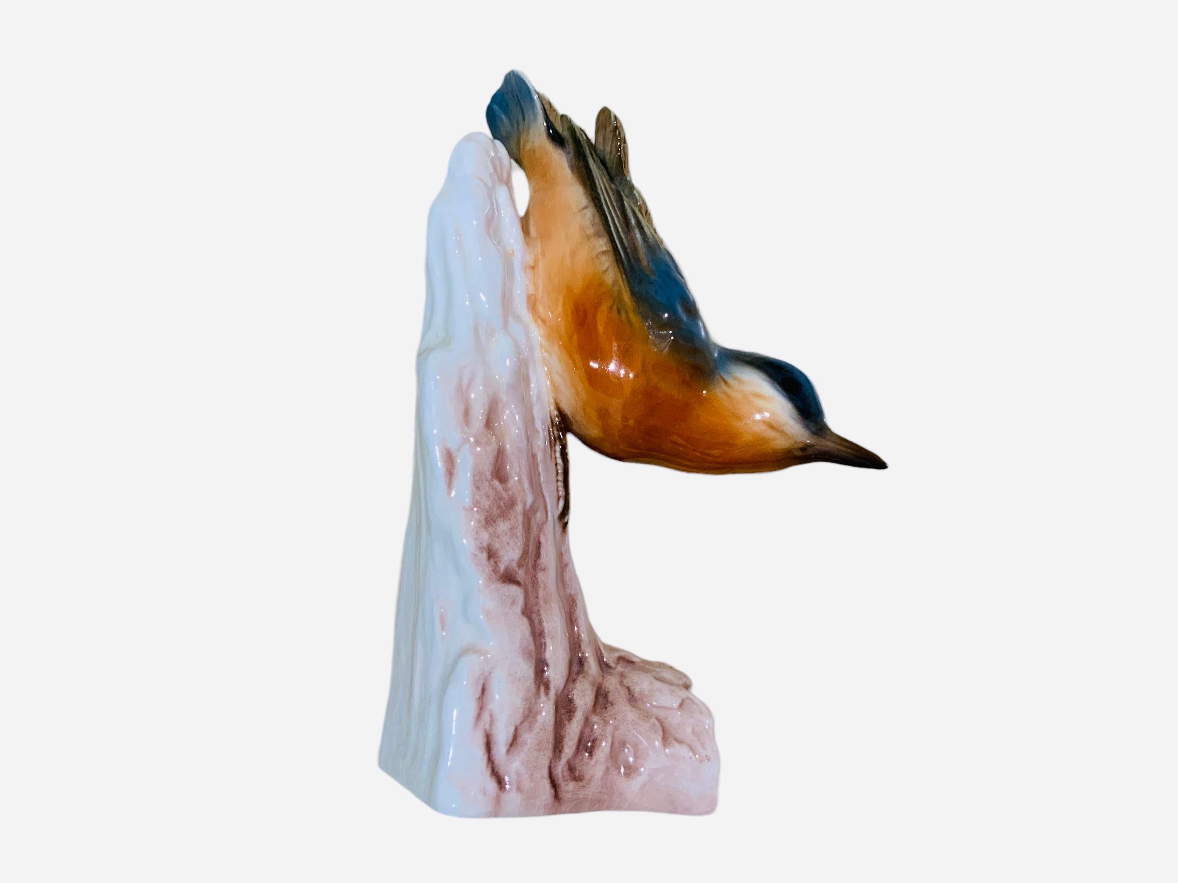 This is a Goebel porcelain figurine of a bird. It depicts a very well done hand painted Nuthatch. This colorful bird is standing over an old aged trunk. It is hallmarked Goebel, W.Germany below the base of this trunk.