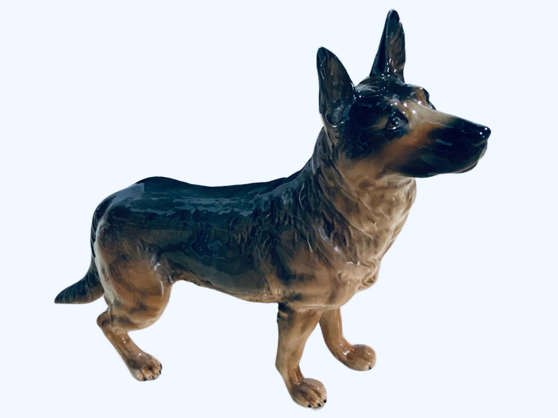 This is a Goeble porcelain figurine of a dog. It depicts a very well done hand painted German Shepherd dog. He is standing up very proud of himself, but with a sweet gaze. The Goeble hallmark is below the figurine.