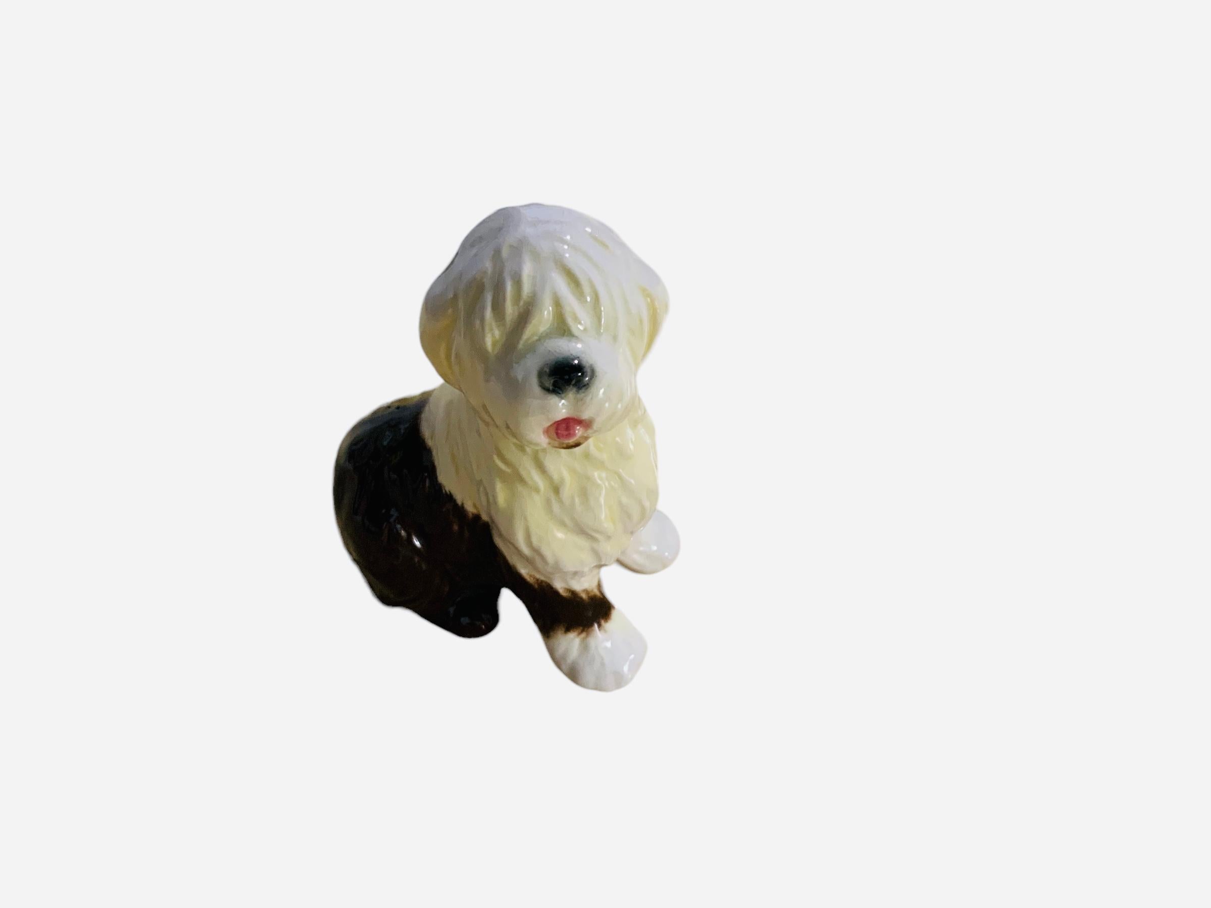 This is a Goeble porcelain figurine of a dog. It depicts a hand painted adorable Old English Sheep dog standing up and full of white and dark brown hair. The Goeble hallmark is below the figurine.