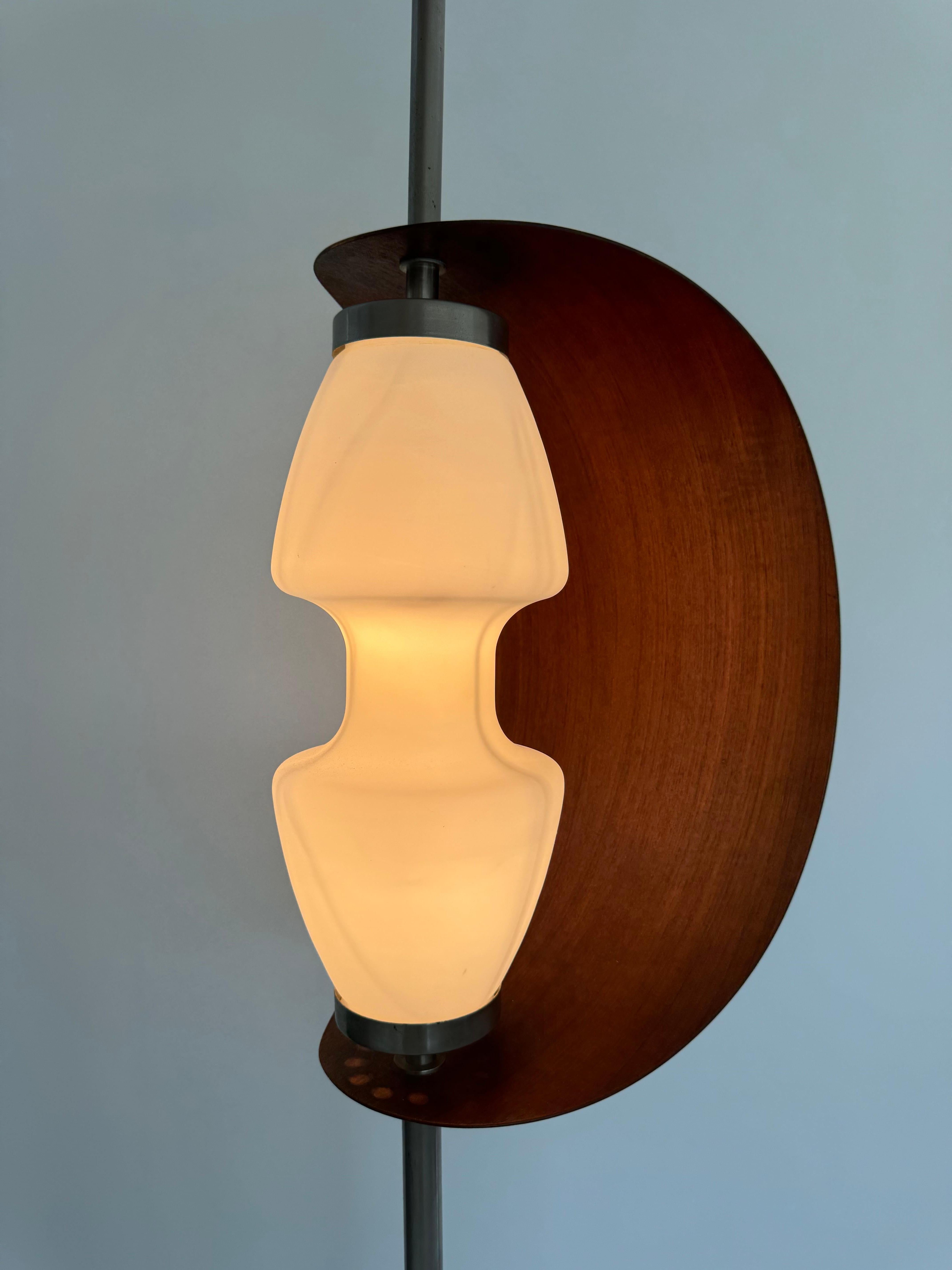 
Rara lampada da terra di design di Goffredo Reggiani, edizione Studio A.

Base circolare in marmo italiano, stelo cilindrico cromato sormontato da un globo opalino bianco e avvolto da una lama rotante in teak a forma di vela.

Fabbricazione e