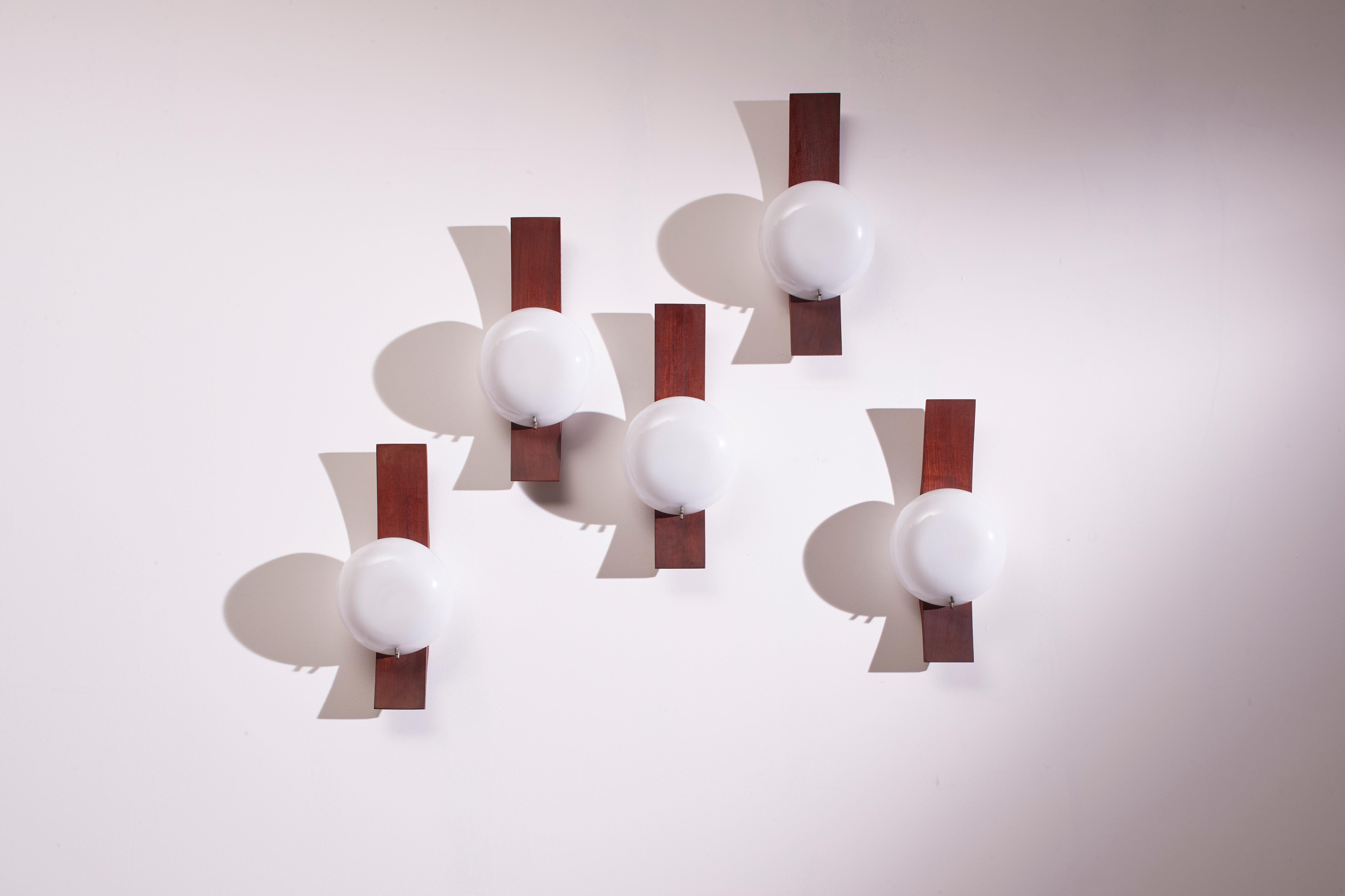 A set of five elegant teak and perspex wall lamps, designed and produced by Goffredo Reggiani in the 1960s, represents an example of refined design. These lamps stand out for their clean style that harnesses the simple and rigorous lines of the