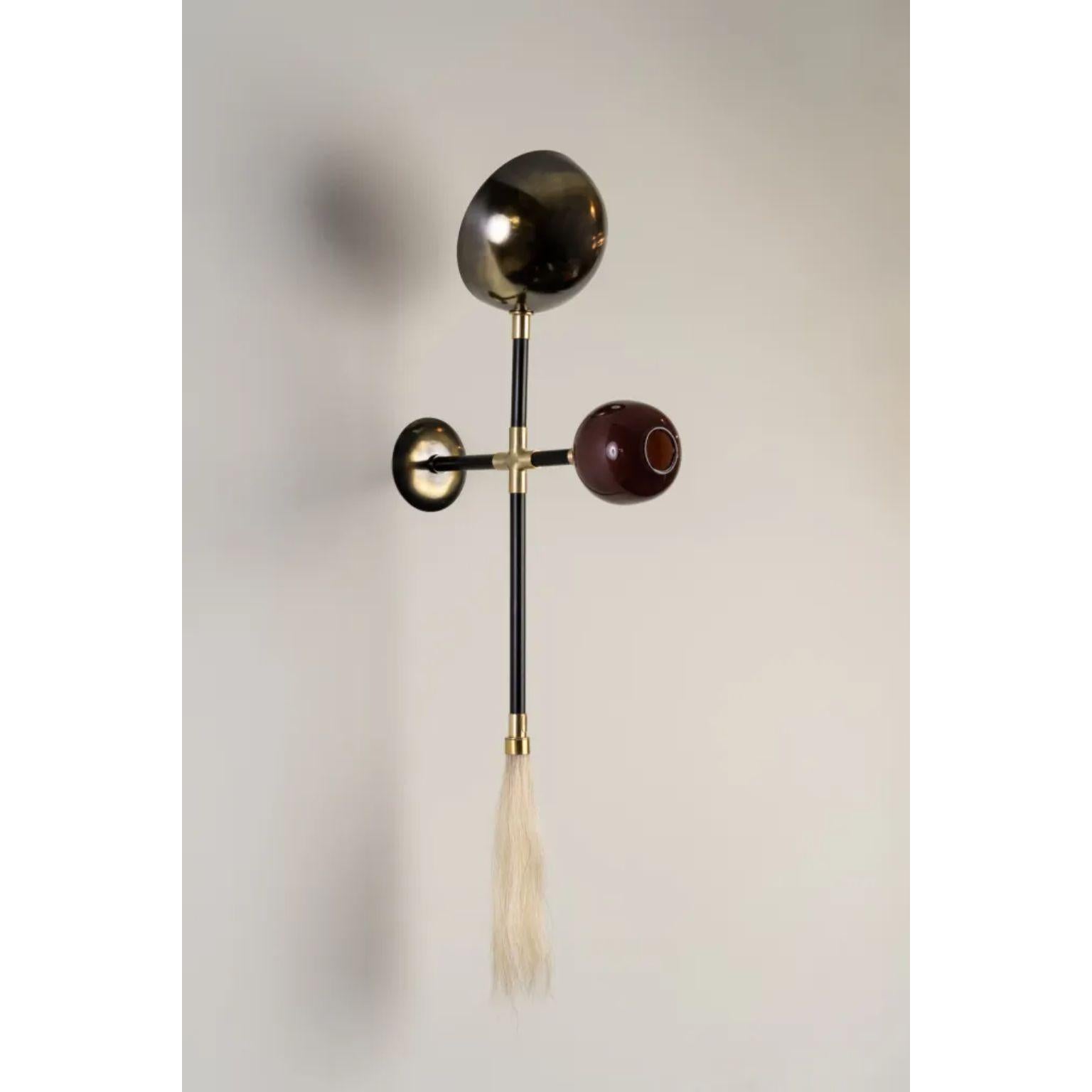 Gogo Aubergine Wall Lamp by Isabel Moncada
Dimensions: D 21 x W 40 x H 95 cm.
Materials: Brass with black finish and polished brass, blown glass globe and horsehair tassel.

Go-go, a term used in the 60’s to describe a frantic, pulsating expression