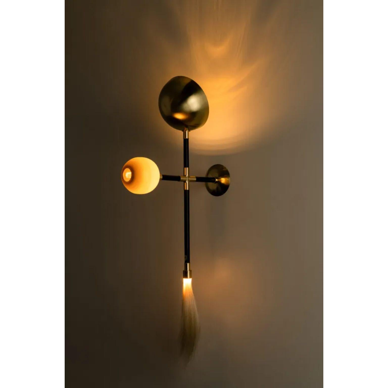 Gogo Olive Wall Lamp by Isabel Moncada
Dimensions: D 21 x W 40 x H 95 cm.
Materials: Brass with black finish and polished brass, blown glass globe and horsehair tassel.

Go-go, a term used in the 60’s to describe a frantic, pulsating expression of