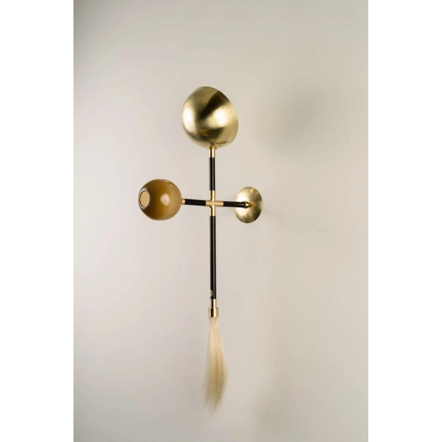 Gogo Sand Wall Lamp by Isabel Moncada
Dimensions: D 21 x W 40 x H 95 cm.
Materials: Brass with black finish and polished brass, blown glass globe and horsehair tassel.

Go-go, a term used in the 60’s to describe a frantic, pulsating expression of