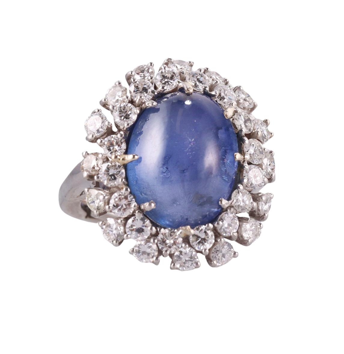 Impressive 18k gold ring with center oval cabochon sapphire - approx. 15.20ct (stone measures 14.8 x 11.6 x 8.2mm), surrounded with approx. 2.00ctw SI1/H diamonds. Ring size 5, top is 24mm x 21mm. Tested 18k, not marked. Weight 15.8 grams.