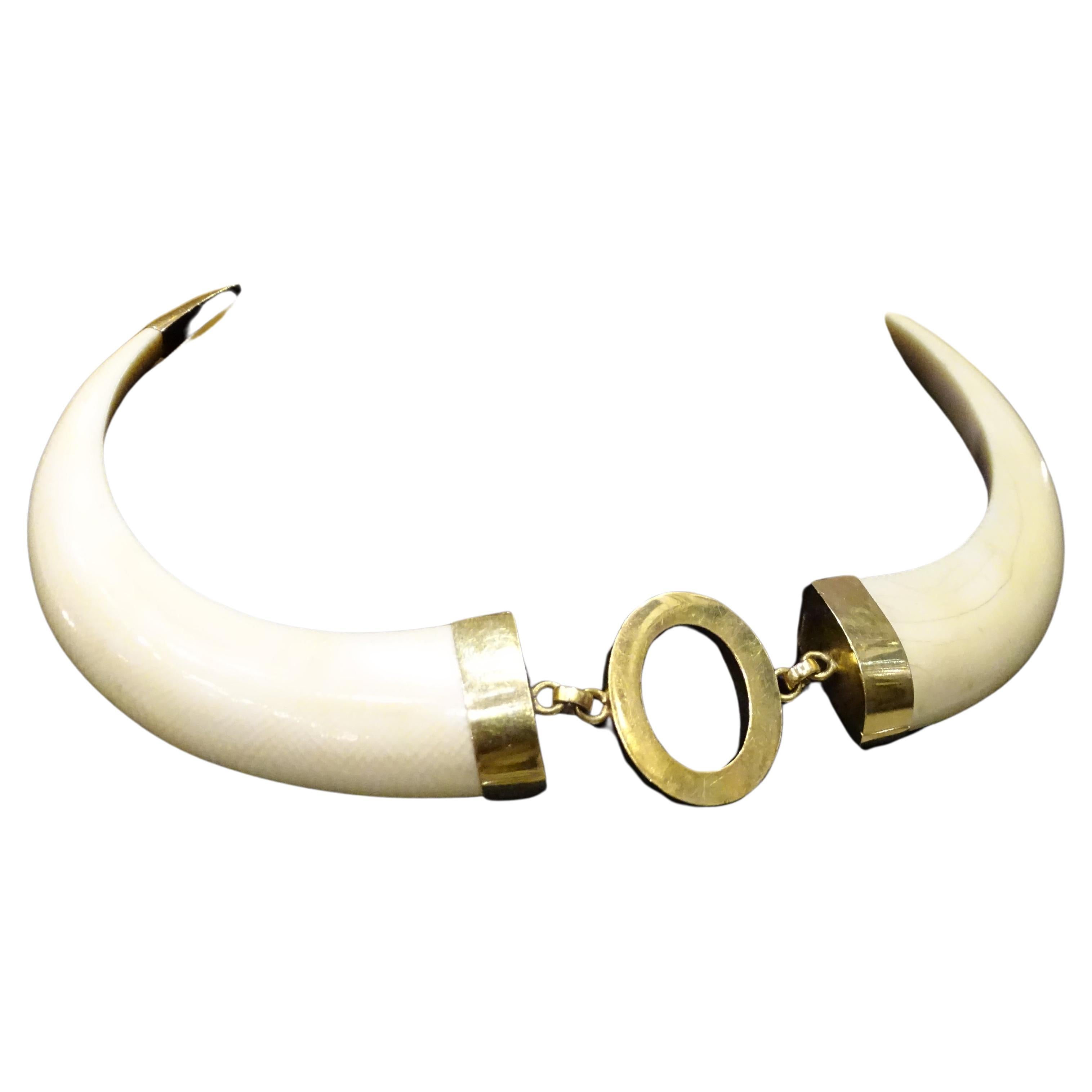 Wunderschöne Halskette aus zwei polierten Knochenstücken in Form eines Stoßzahns. Die Fassung, die Schließe und das zentrale ovale Motiv sind aus 18-karätigem Gold gefertigt. Die Länge ist dank der Kettenglieder verstellbar. Hakenverschluss. Elegant