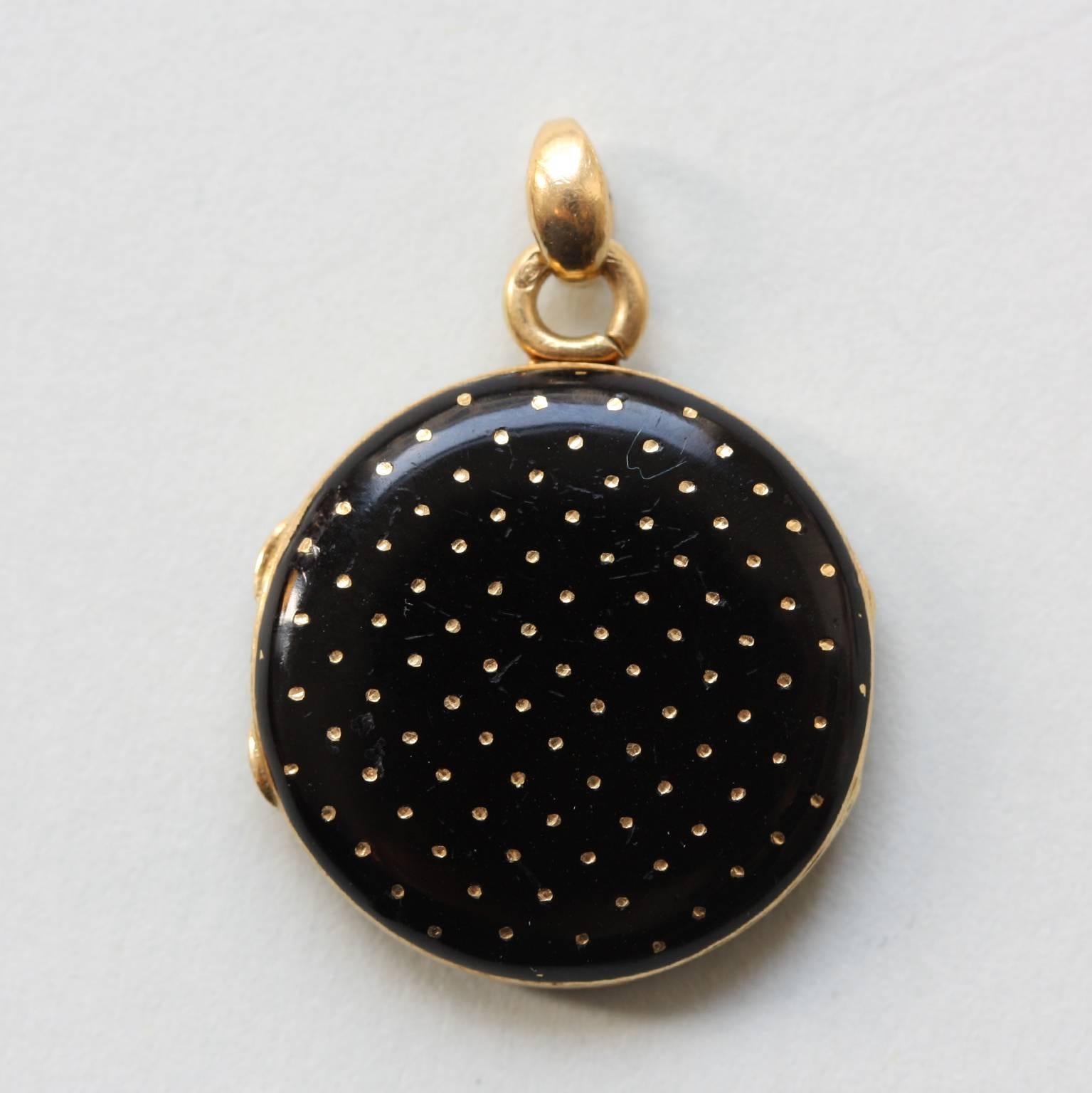 An 18 carat gold round locket with one compartment decorated with black enamel and gold dots on it, 19th century France.

weight: 6.05 grams
dimensions: 2.7 x 1.9 cm
tiny repair to the enamel 