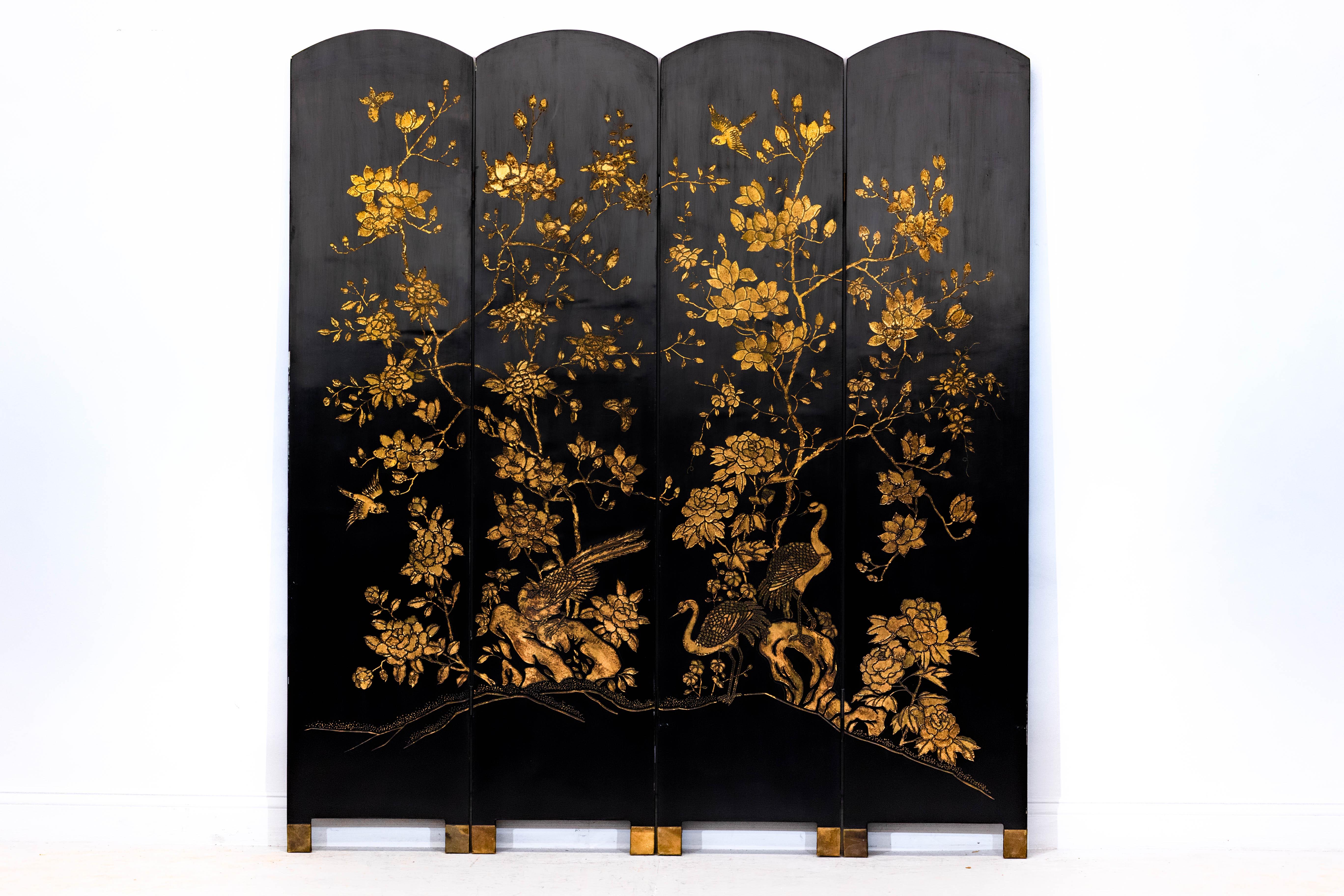 This vintage Chinese folding screen features four arched panels, richly lacquered in deep black and decorated with intricate gilt motifs. The front face showcases a luminous composition of flowering branches and elegant birds—cranes, peacocks,