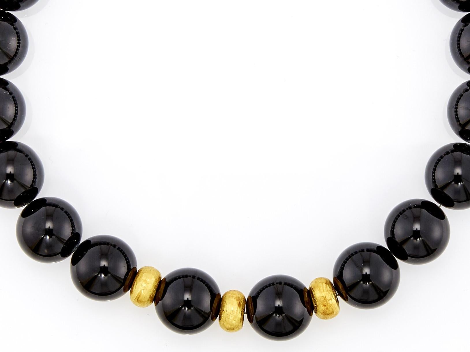 Questa collana è composta da 20 perline di onice nero, di dimensioni comprese tra 20 e 19,7 mm, con perline e chiusura in oro 18 carati, infilate in un cordoncino di metallo. 