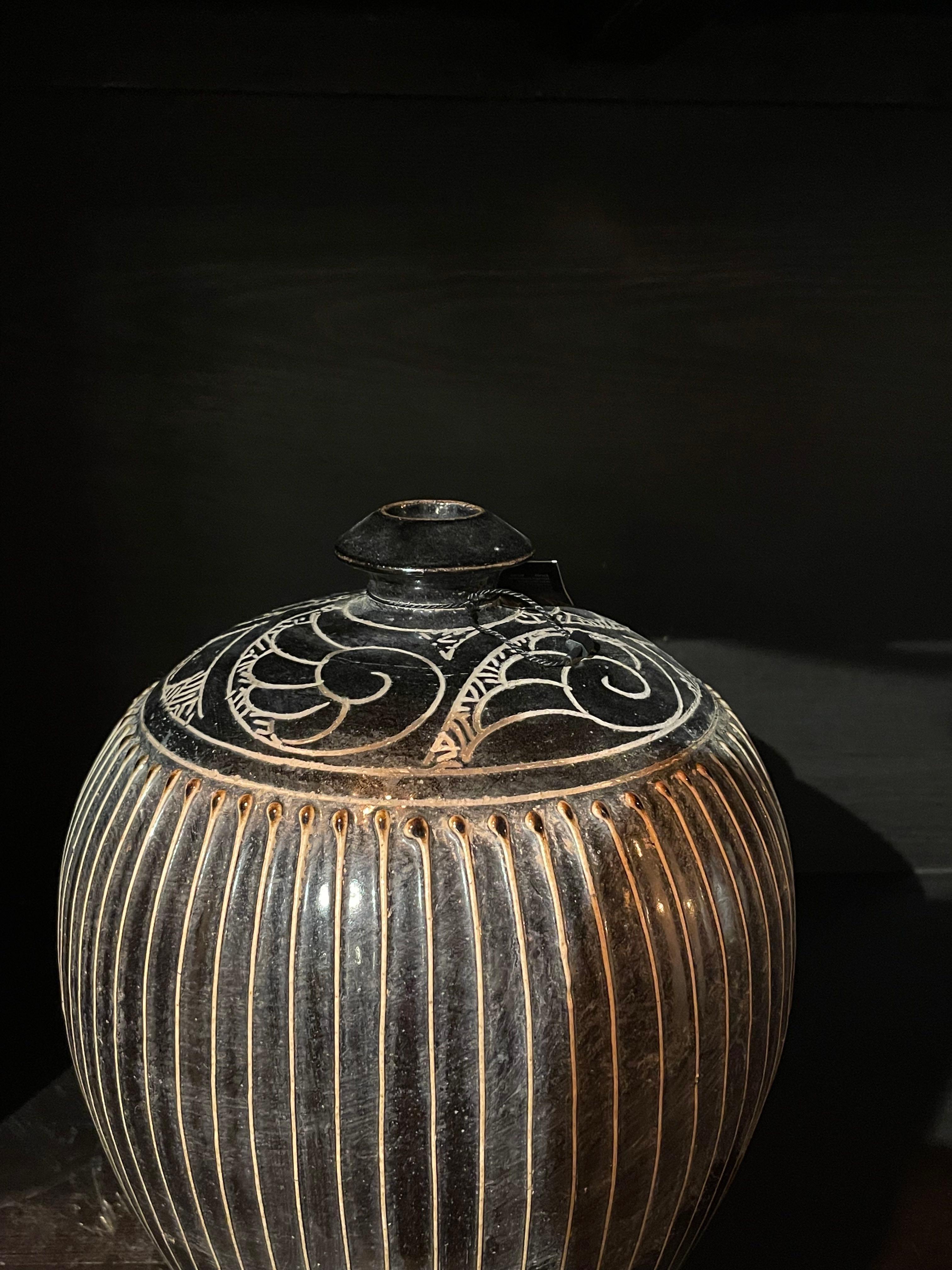 Contemporary Chinese black and gold stripe vase with 
decorative design on top of rounded shaped vase.
