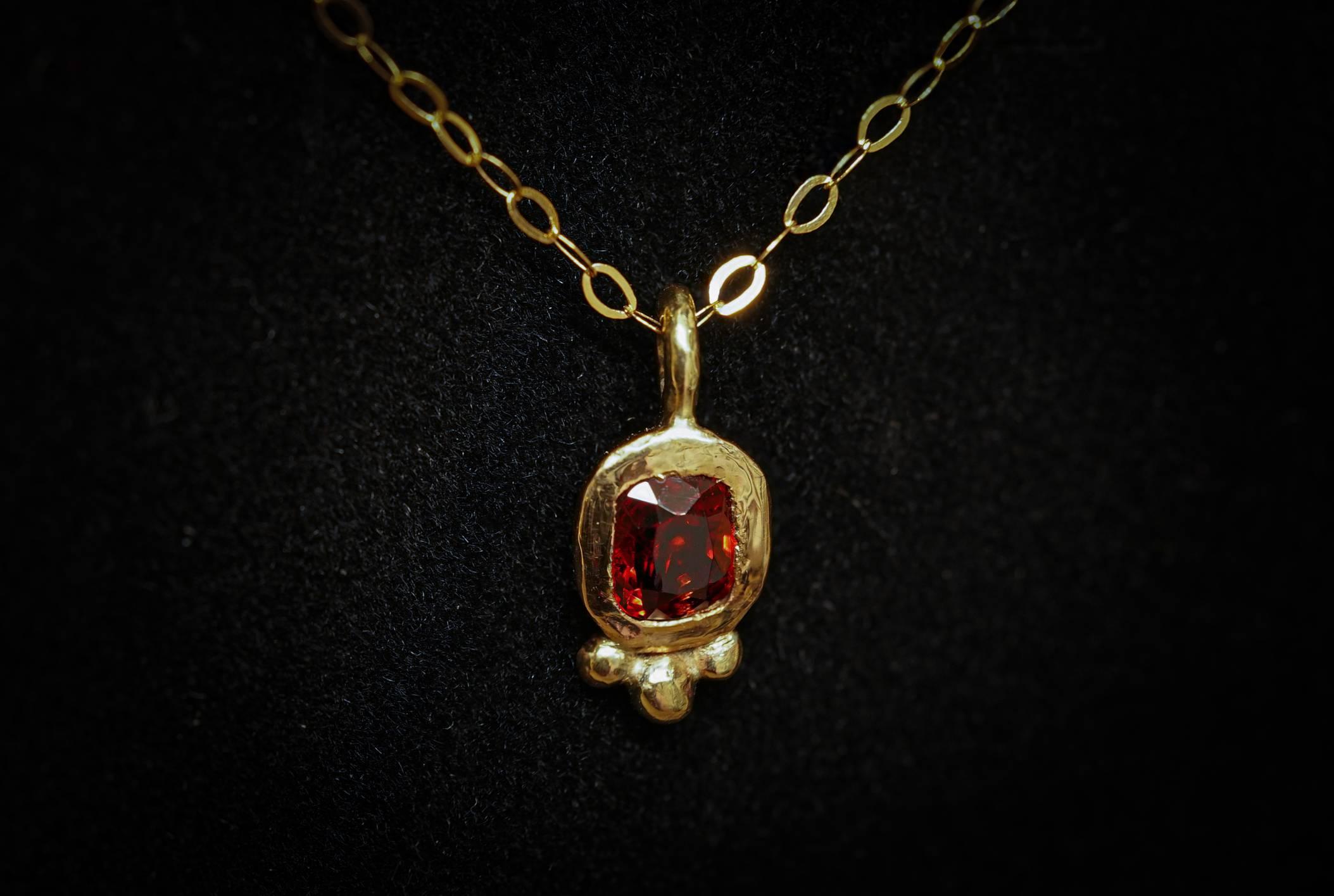 A rich red Burmese spinel from Mogok set within a byzantine style 9ct gold pendant. The pendant comes on a dainty 18inch 9ct gold trace chain.