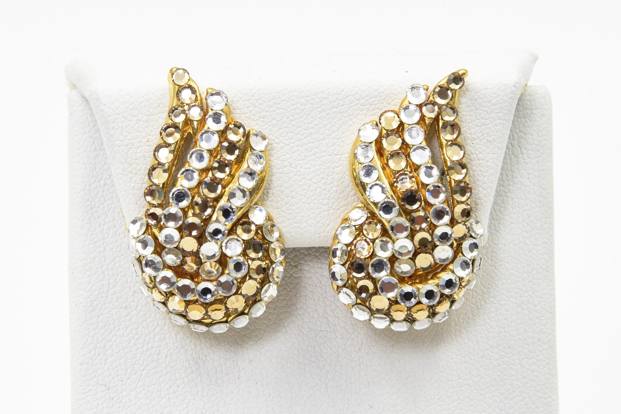 Stunning earrings featuring clear and gold tone crystals that produce a swirl ribbon design on the ear.  Mounted in a gold toned metal, these earrings have a clip-on back.