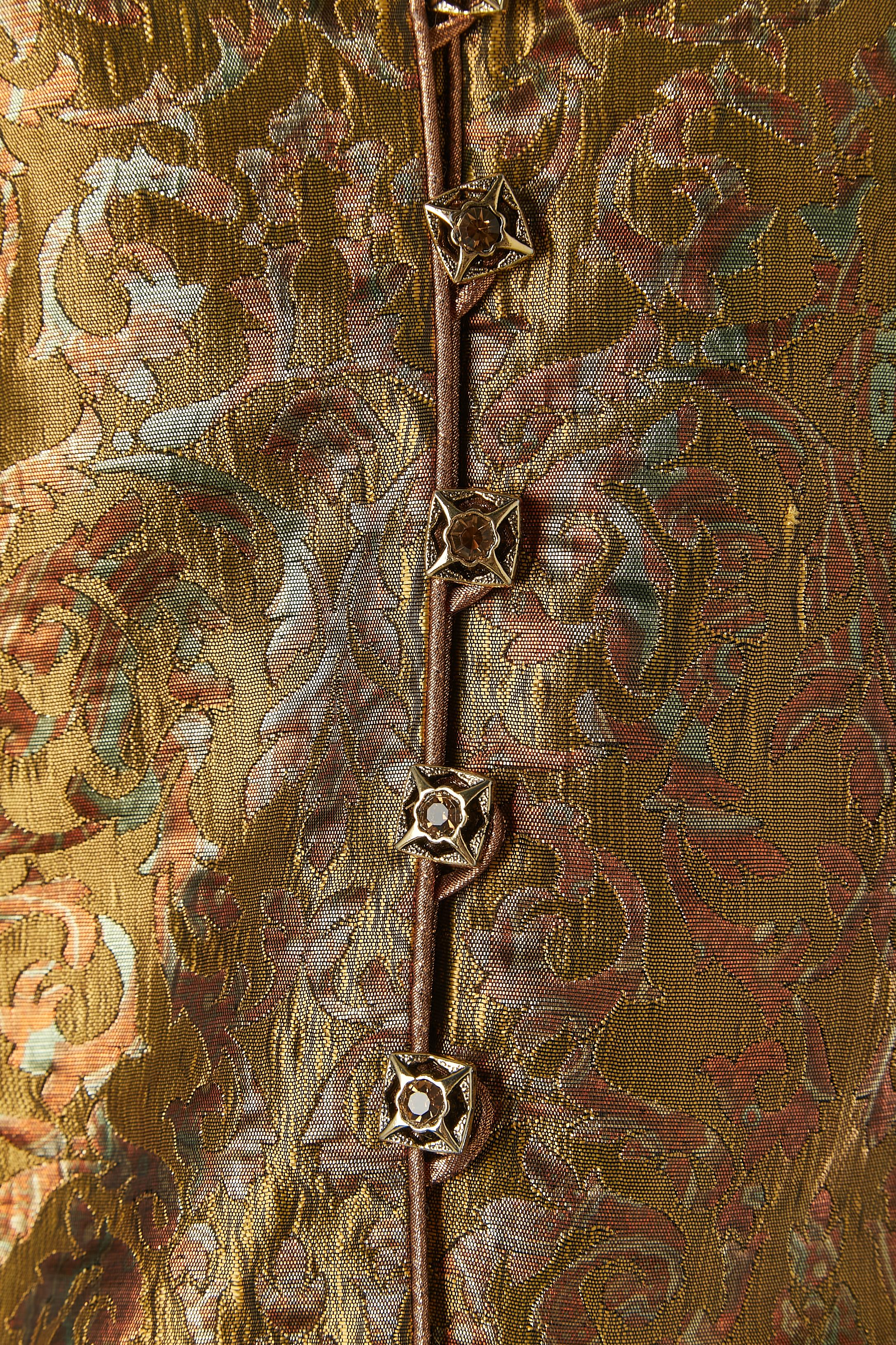Gold and copper brocade skirt suit . Main fabric: 50% polyester, 34% rayon, 16% polyester metal. Lining: 100% polyester. 
Shoulder-pad. Piping. Jewellery button and buttonhole closure on the middle front with snap underneath. 
SIZE 10 (US) 40 (Fr) 