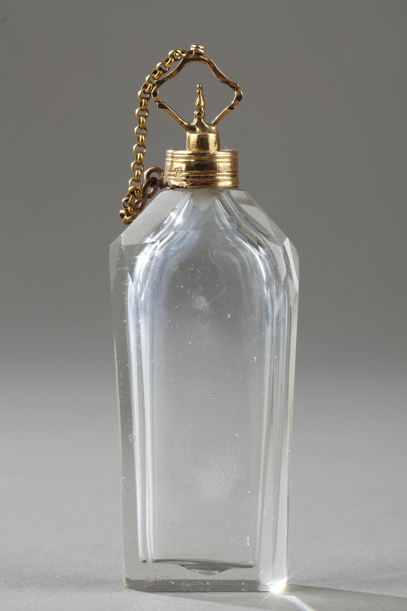 Crystal bottle blown and cut, 18-carat gold setting.A band of gold encircles the neck and base of the flask, and the openwork, gold stopper is connected to the neck with a thin, gold chain.

Gold mark of recense end of 18th century.

Louis XVI