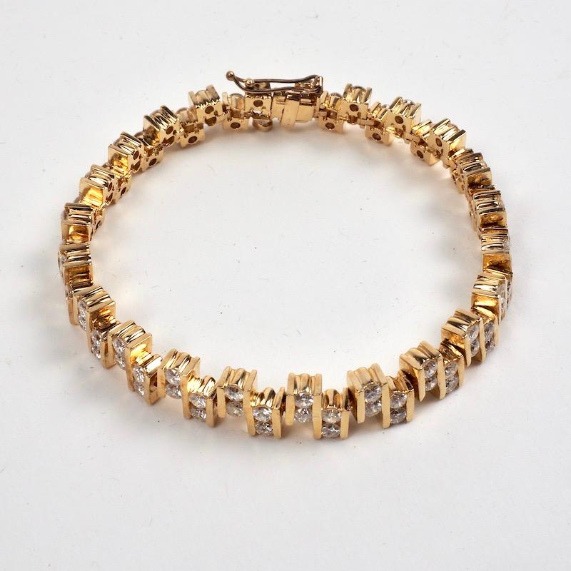 A beautiful gold link eternity bracelet consisting of 92 round brilliant cut diamonds set in alternating pairs. The diamonds are channel set and weigh approx. 5.50 Ct. Rated VS-SI in clarity and G-H in colour. Locking closure with  heart shaped