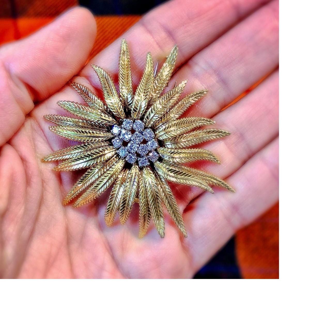 A French 18 karat gold flower brooch with diamonds by Cartier. The brooch is composed of highly textured carved foliate motifs and has 14 round-cut diamonds serving as an attractive center to the bloom, the stones have an approximate total weight of