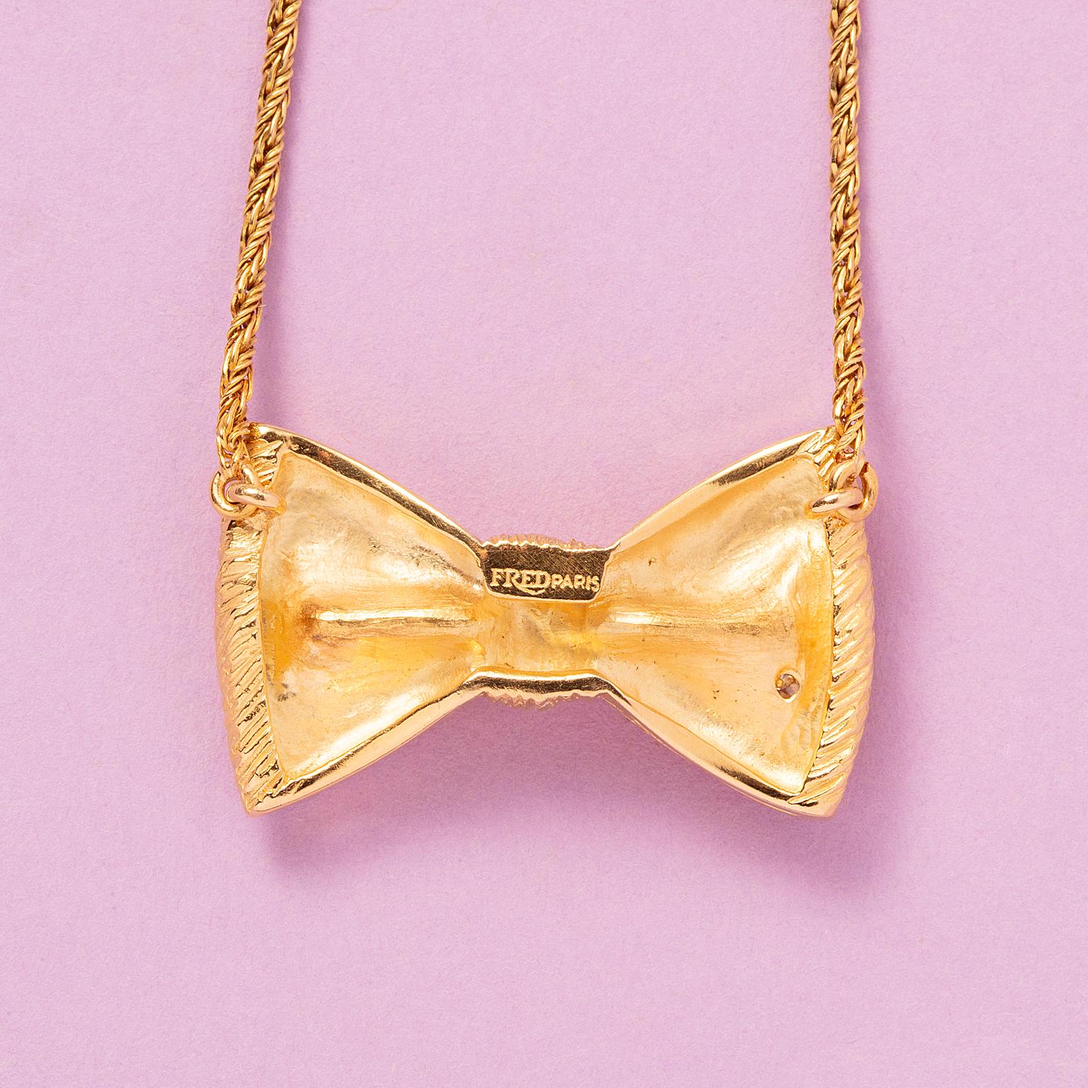 An 18-carat gold necklace with a bow finely engraved and set with one brilliant-cut diamond, signed: Fred, Paris, circa 1970.

weight: 11.3 g 
length: 37 cm 
dimensions bow: 29 x 17 cm