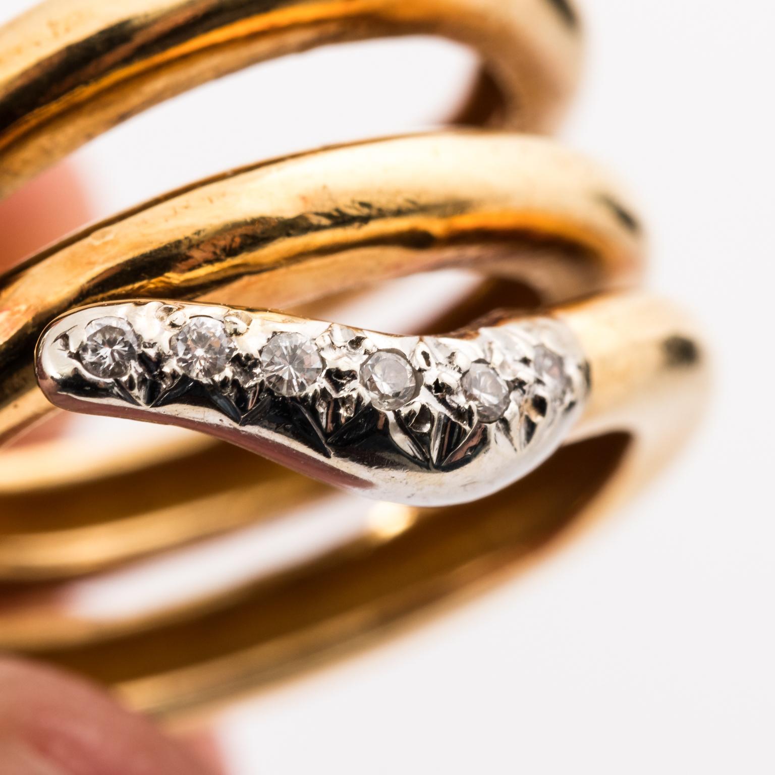 Circa 1950-1960 three band 18 karat gold snake ring with pave cut diamonds featured on the tail, serpent head, and neck. The ring also is embellished with two Emerald eyes.
